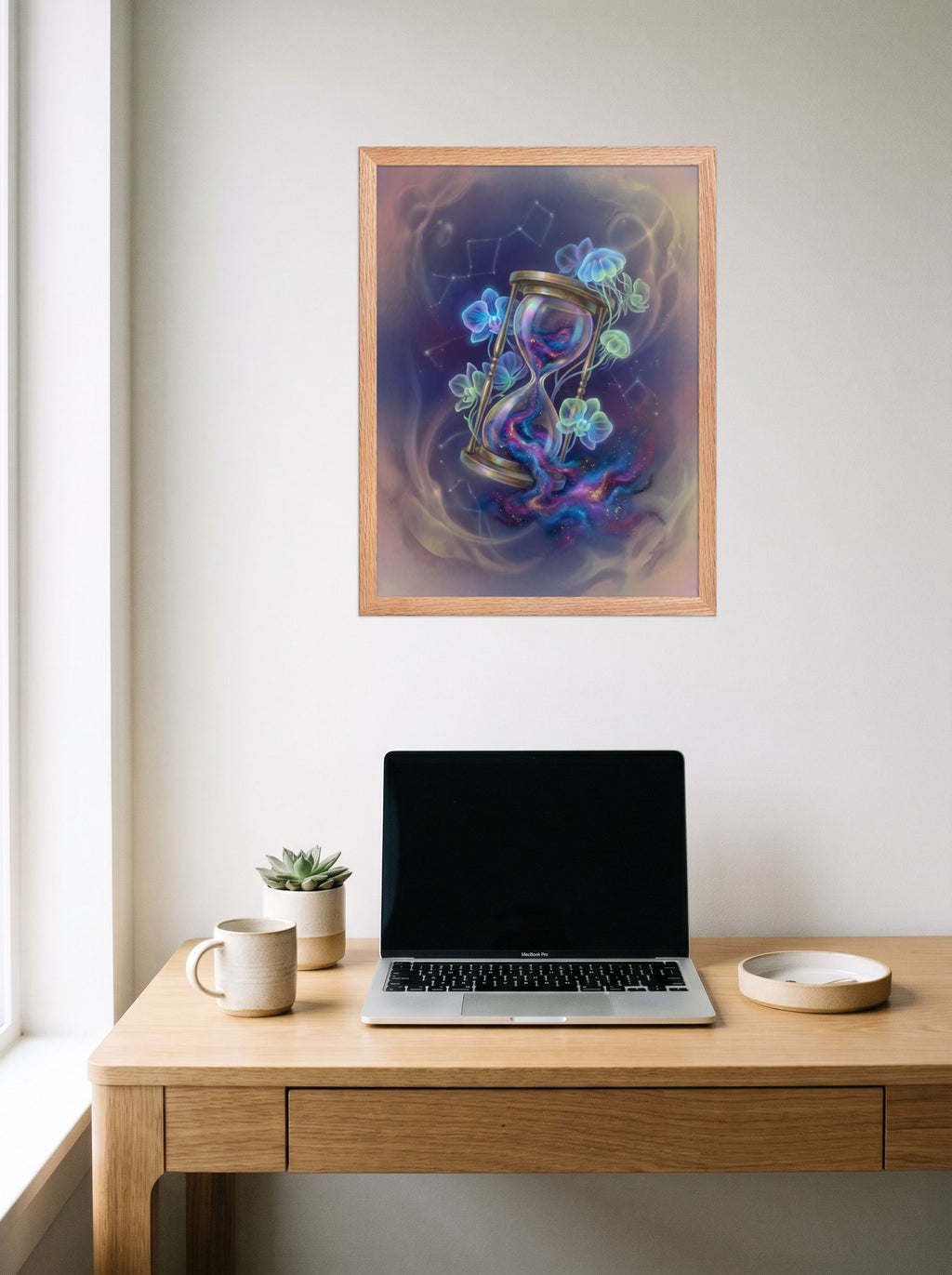 A 18x24 inch redoak framed Magic realism print of 'Sands of the Nebula' hanging above a worktable with a laptop.