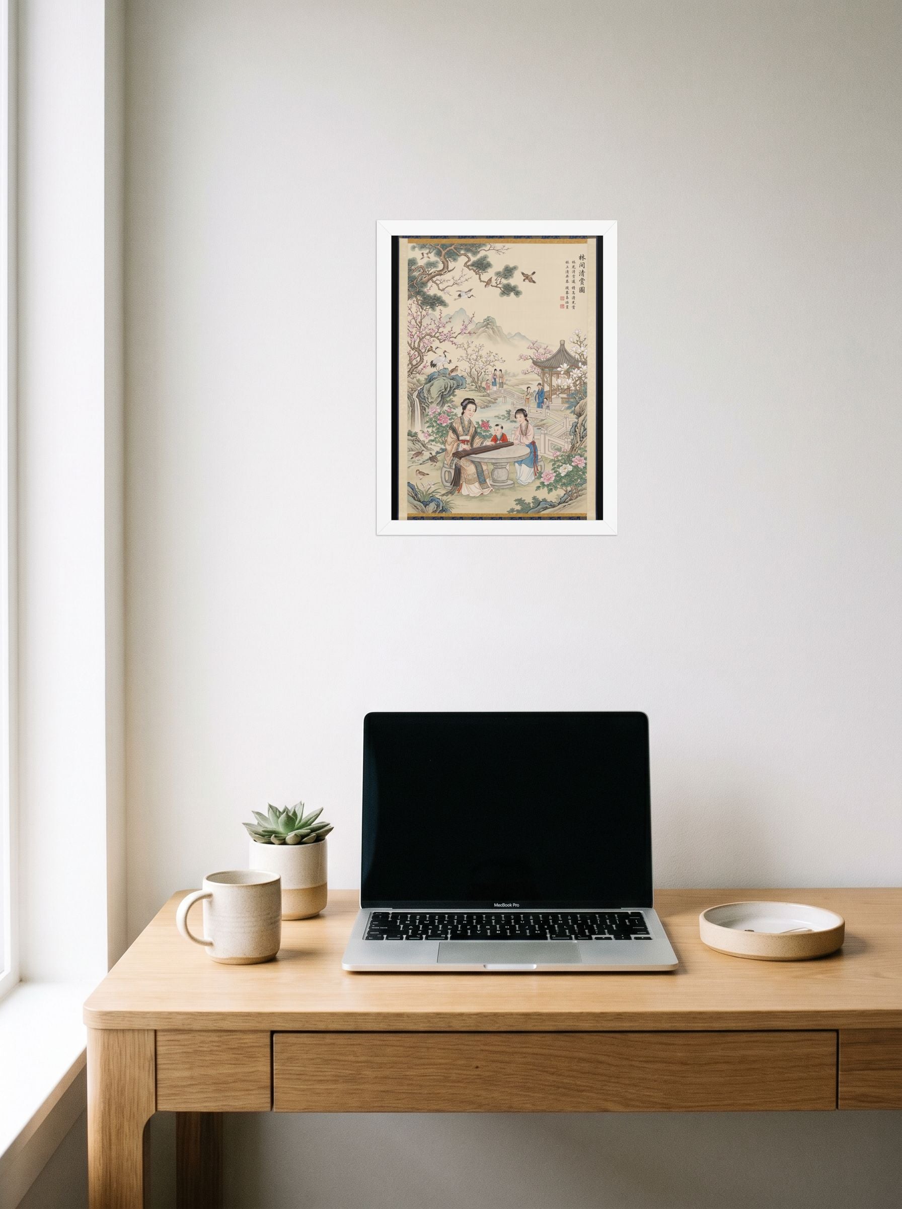 A 12x16 inch white framed Fine Art print of 'Melody in the Spring Garden' hanging above a worktable with a laptop.