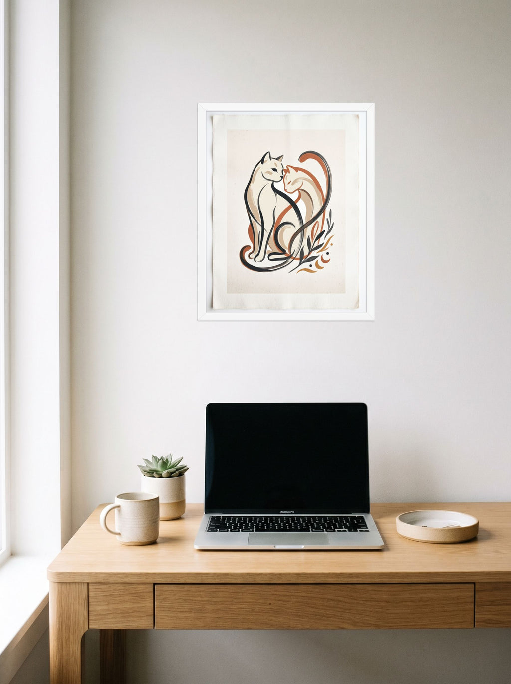 A 16x20 inch white framed Minimalism,Abstract art print of 'Feline Affection' hanging above a worktable with a laptop.
