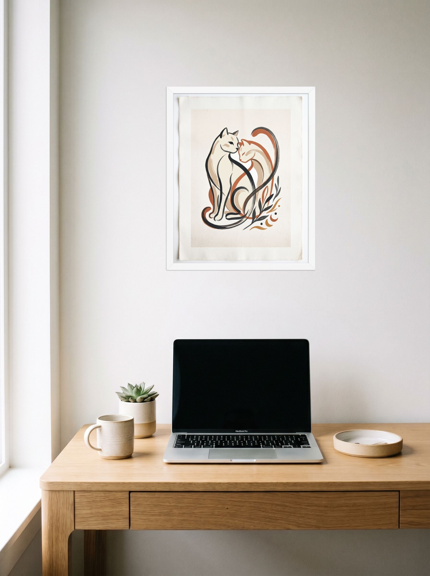 A 16x20 inch white framed Minimalism,Abstract art print of 'Feline Affection' hanging above a worktable with a laptop.