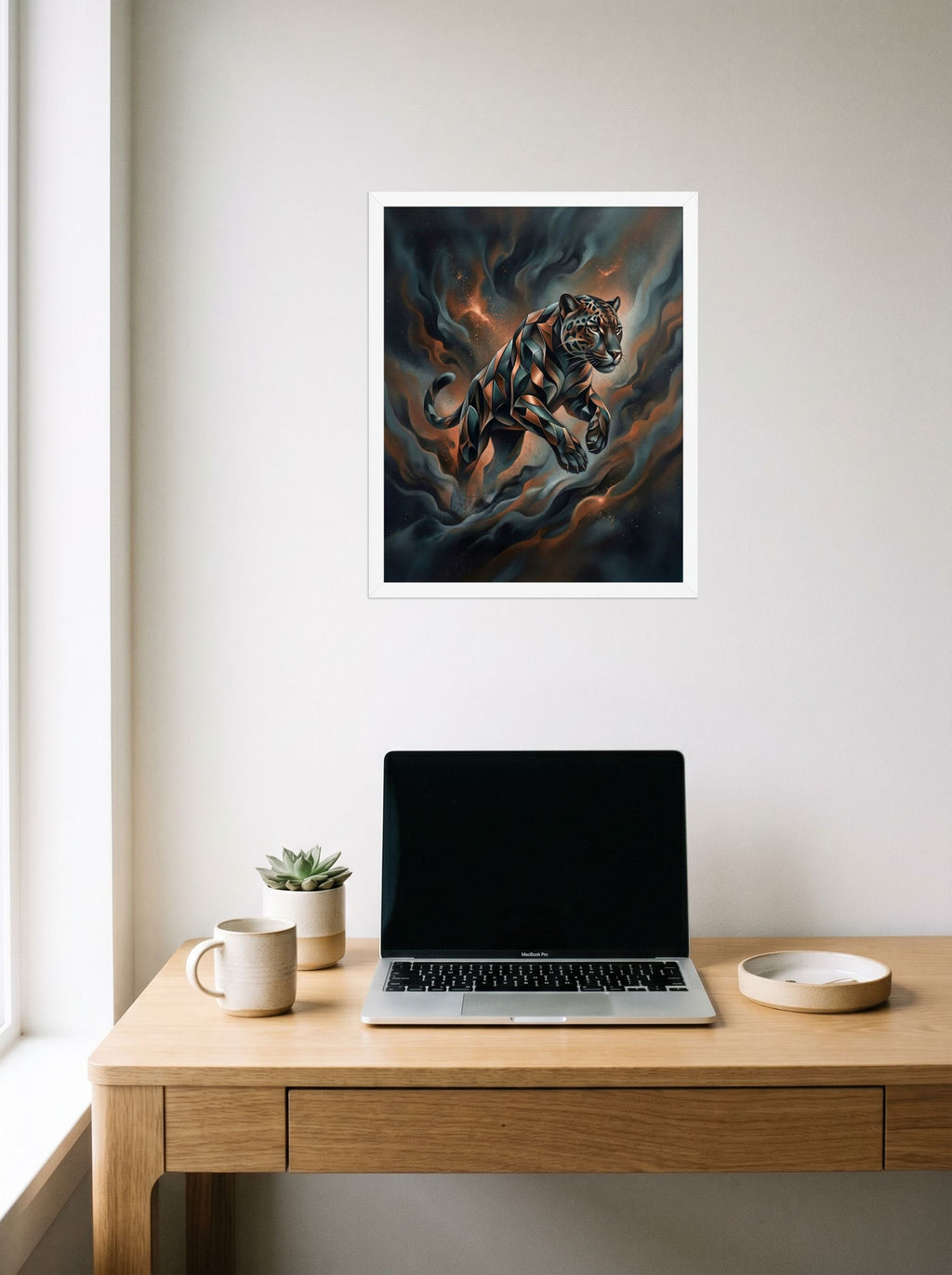 A 16x20 inch white framed Digital art print of 'Phantom Leap' hanging above a worktable with a laptop.
