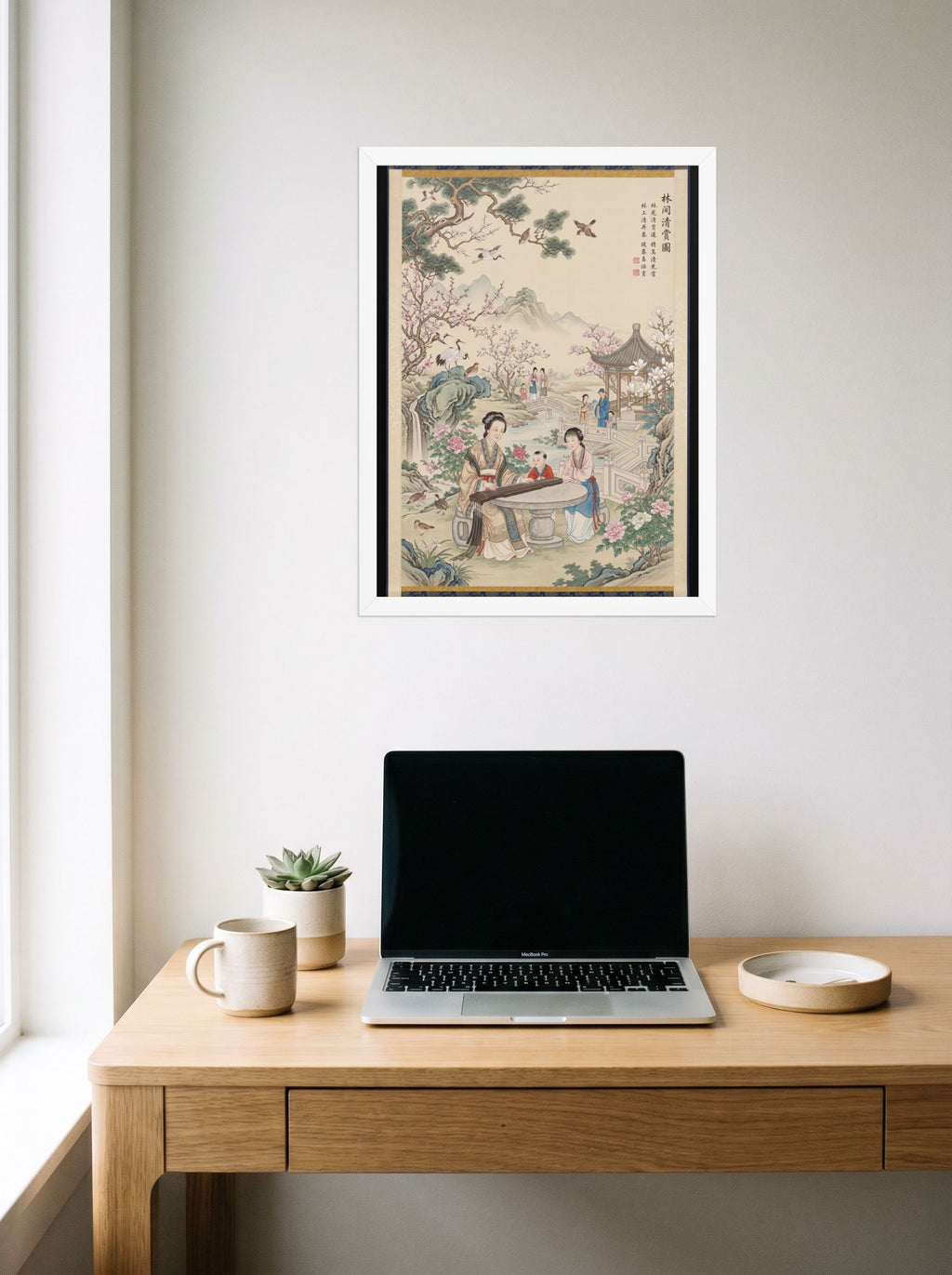 A 18x24 inch white framed Fine Art print of 'Melody in the Spring Garden' hanging above a worktable with a laptop.