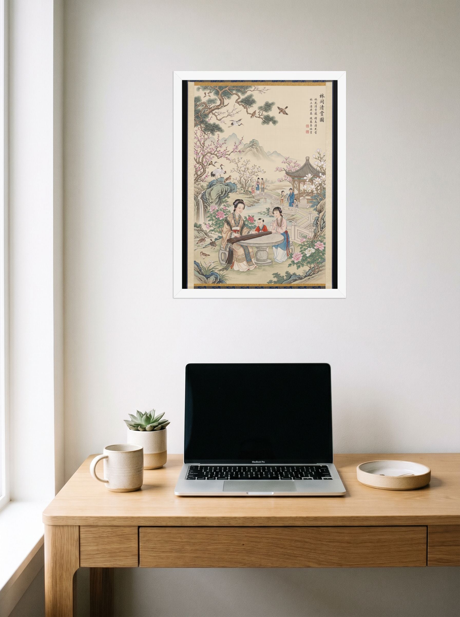 A 18x24 inch white framed Fine Art print of 'Melody in the Spring Garden' hanging above a worktable with a laptop.