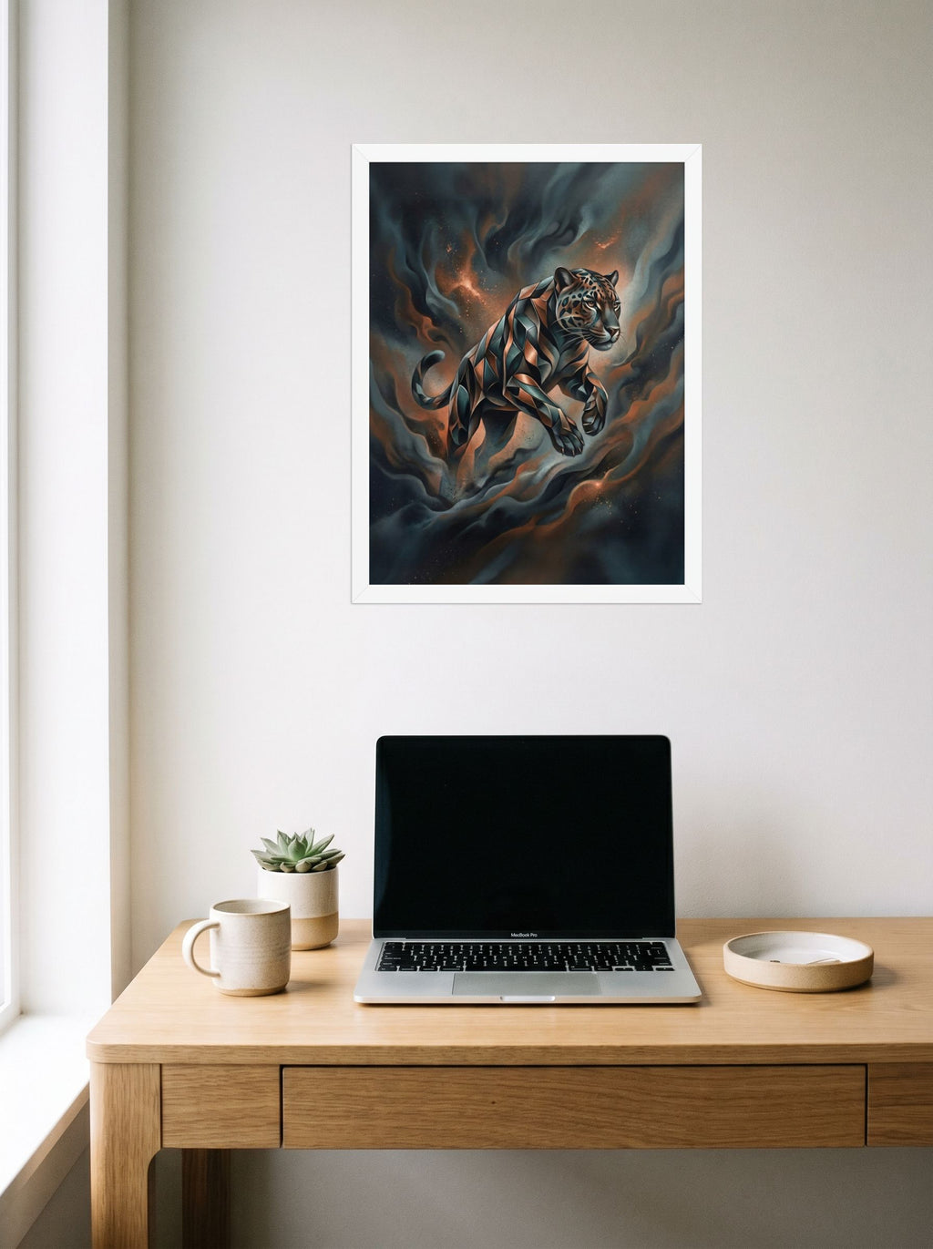 A 18x24 inch white framed Digital art print of 'Phantom Leap' hanging above a worktable with a laptop.