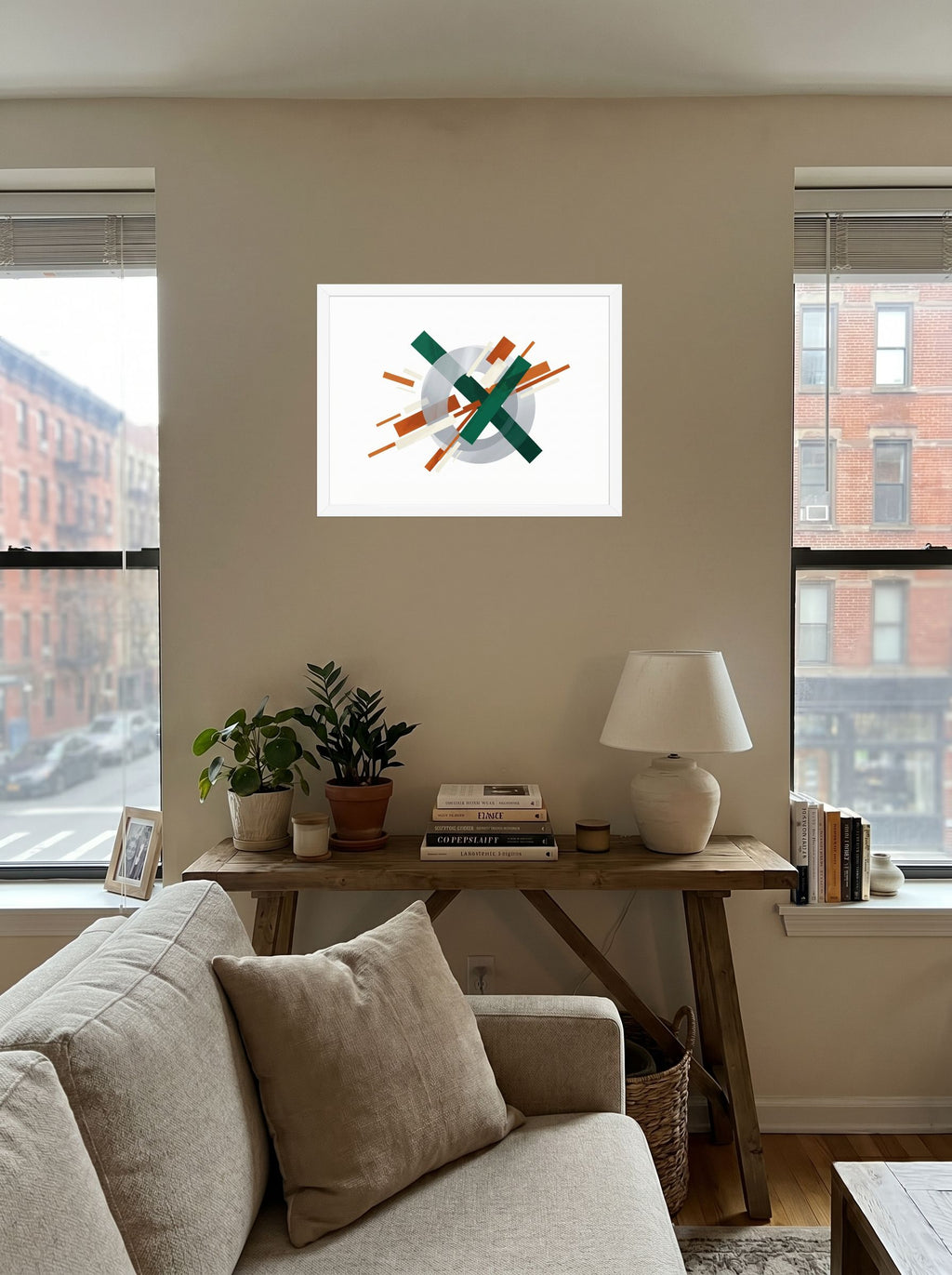 A 24x18 inch white framed Suprematism print of 'Intersecting Perspectives' displayed in the center of a living room.