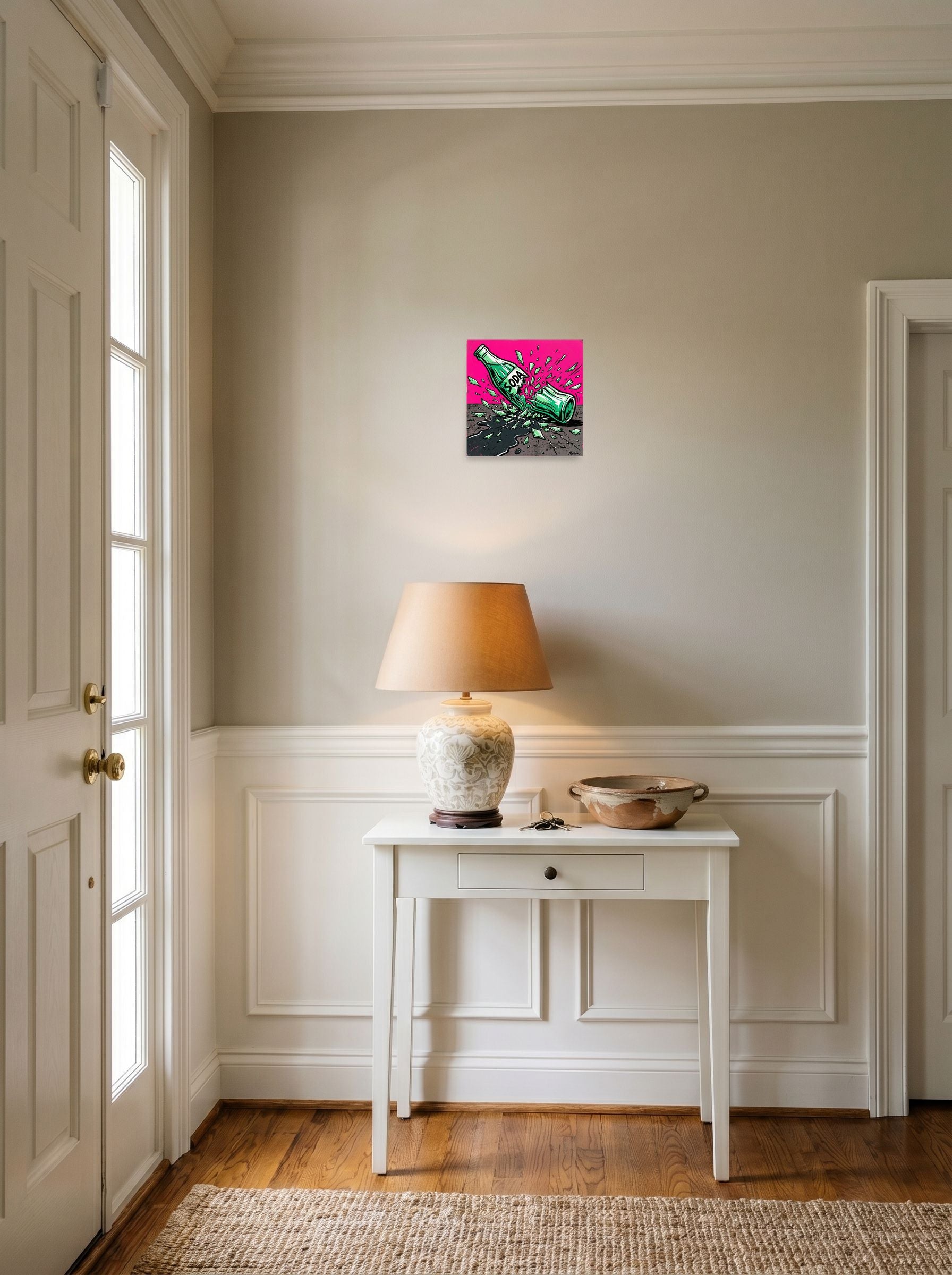 A 10x10 inch unframed paper Pop art print of 'Shattered Soda' hanging in an entryway near a console.