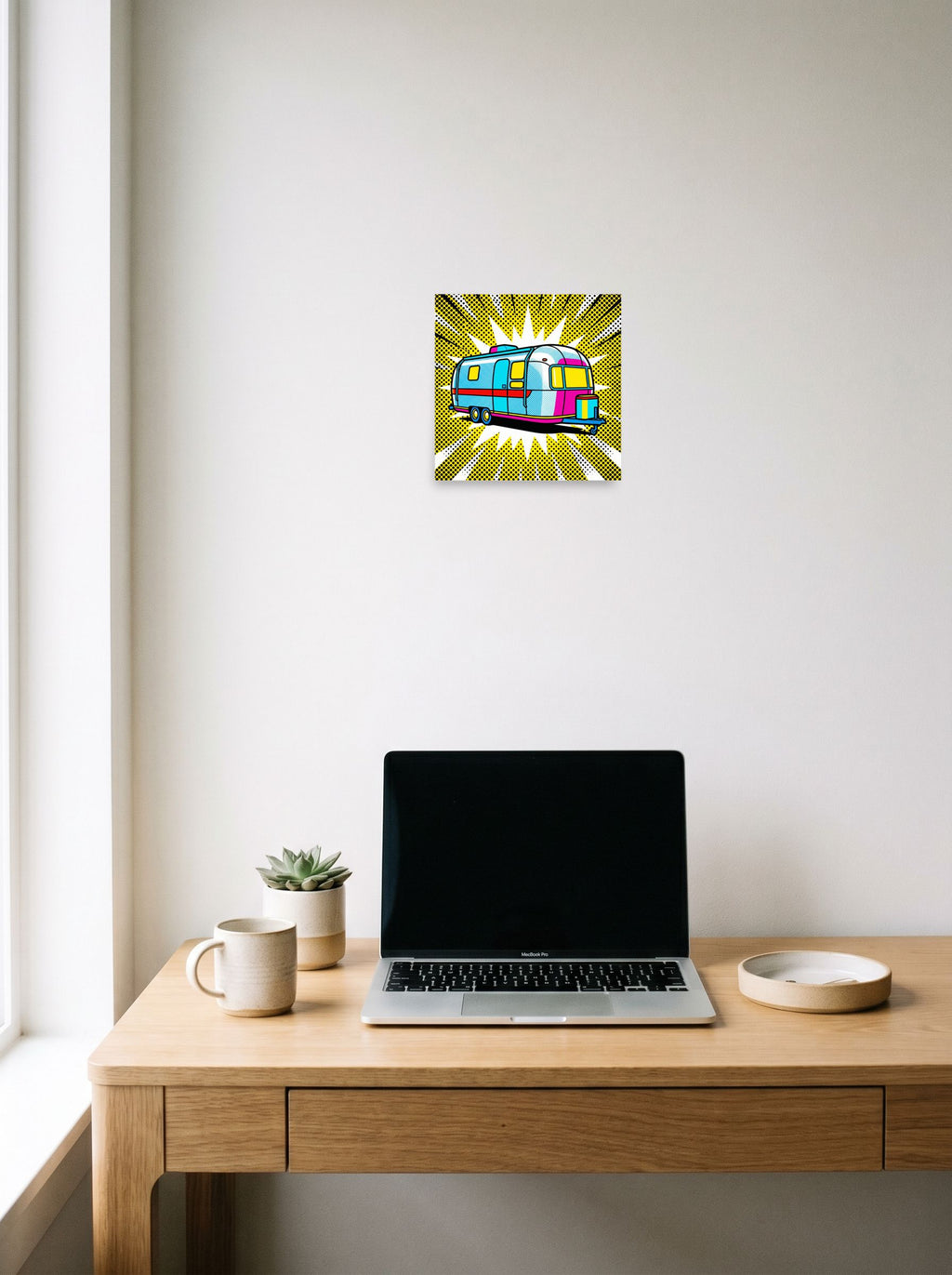 A 10x10 inch unframed paper Pop art print of 'Pop Art Camper' hanging above a worktable with a laptop.