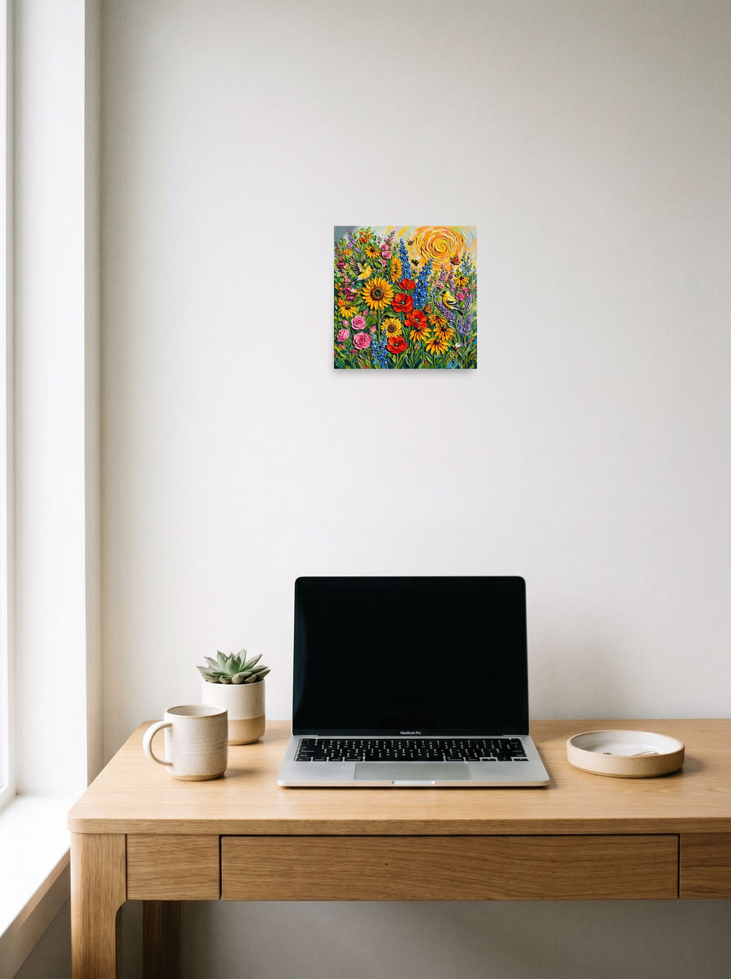 A 10x10 inch unframed paper Expressionism print of 'Sunburst Symphony' hanging above a worktable with a laptop.