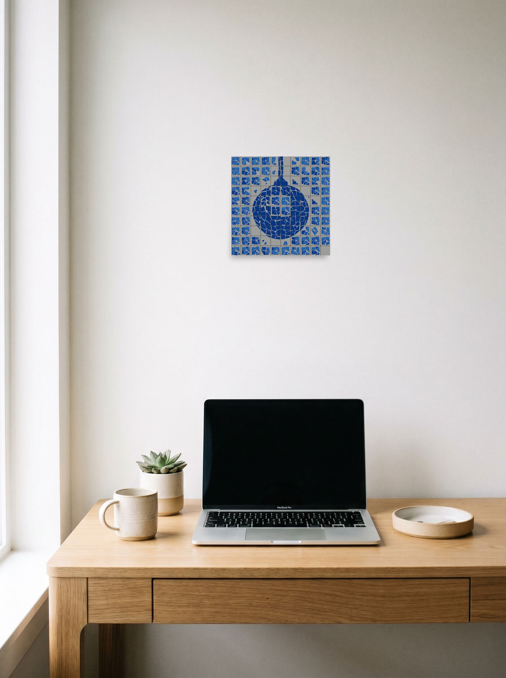 A 10x10 inch unframed paper Pop art print of 'Shattered Groove' hanging above a worktable with a laptop.