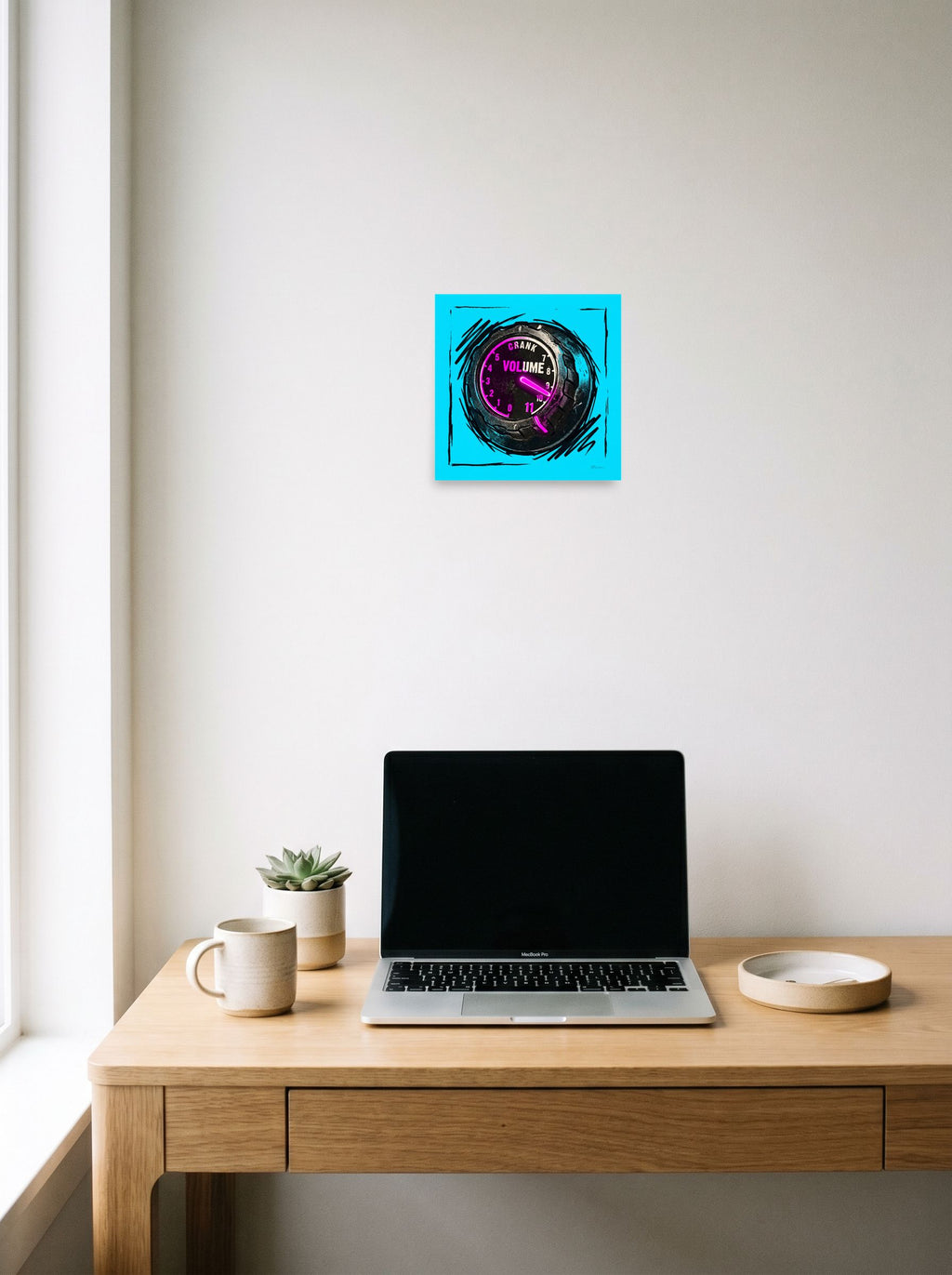 A 10x10 inch unframed paper Pop art print of 'Crank to Eleven' hanging above a worktable with a laptop.