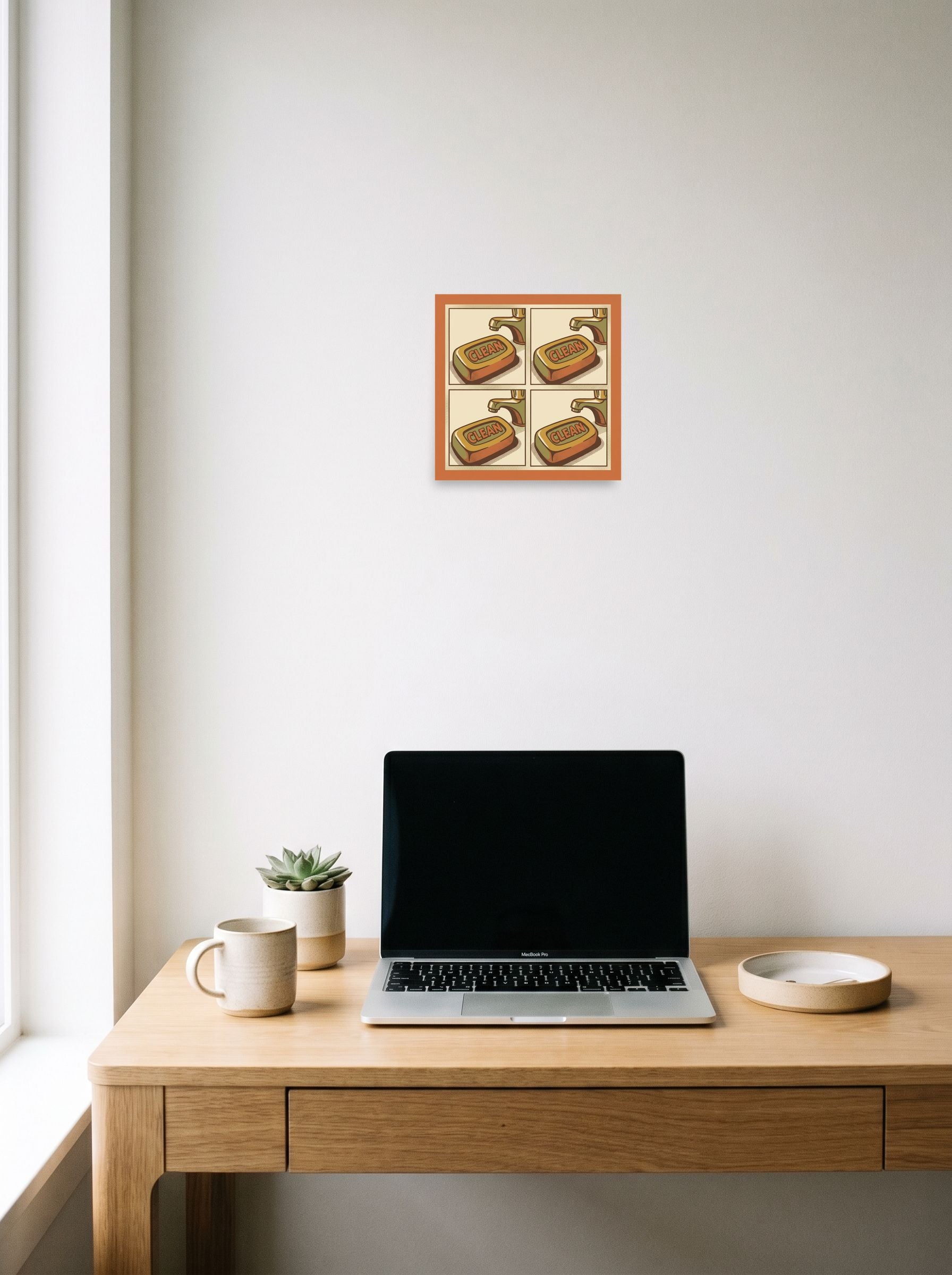 A 10x10 inch unframed paper Pop art print of 'Clean Repetition' hanging above a worktable with a laptop.