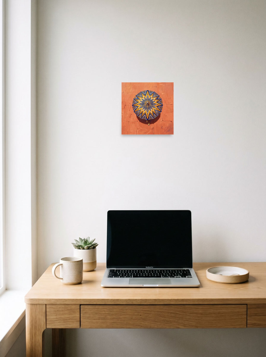 A 10x10 inch unframed paper Geometric abstract art,Figurative art print of 'The Patterned Parasol' hanging above a worktable with a laptop.