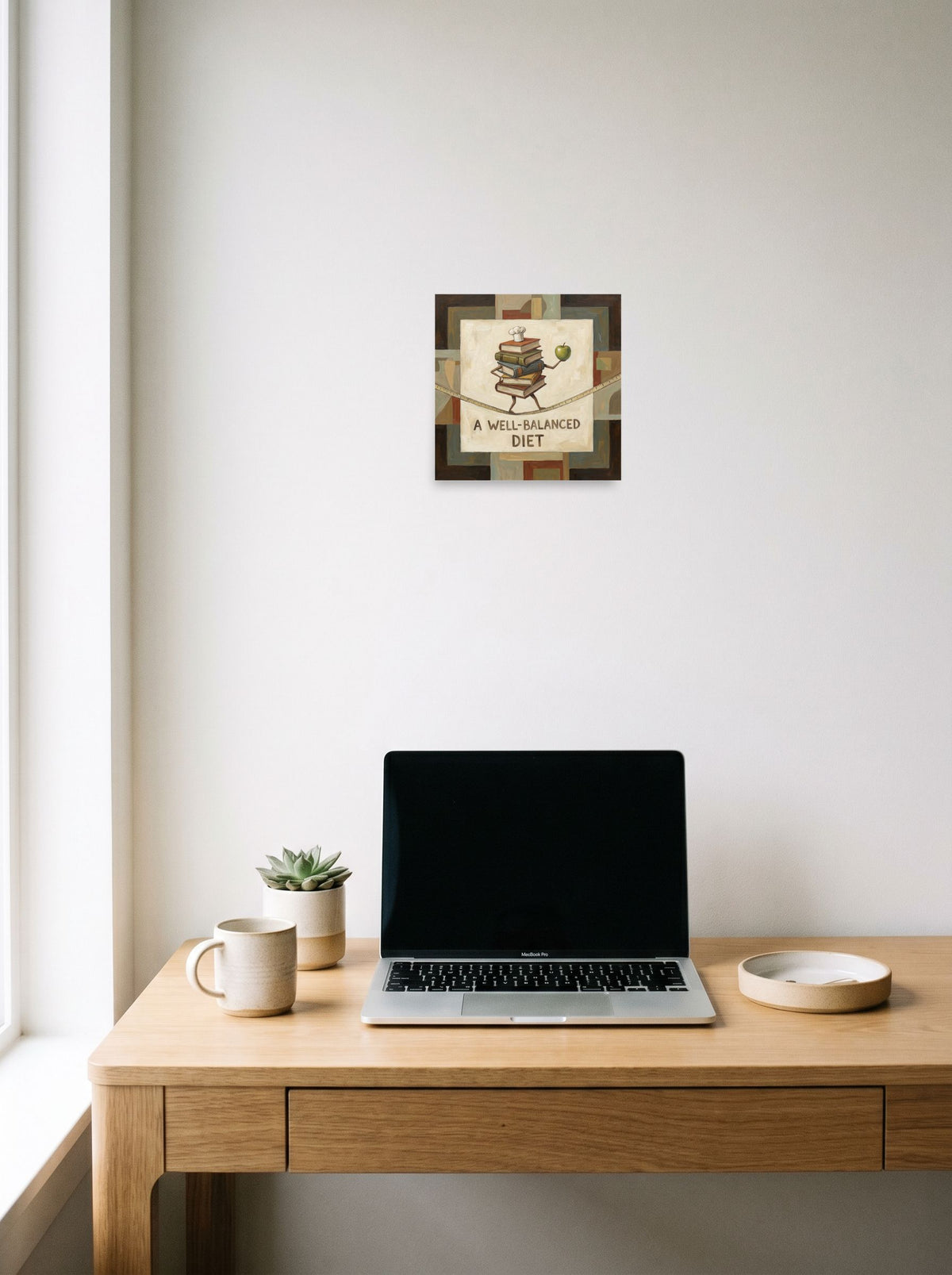 'A Well-Balanced Diet' in 10x10 inch unframed paper, hanging above a worktable with a laptop.