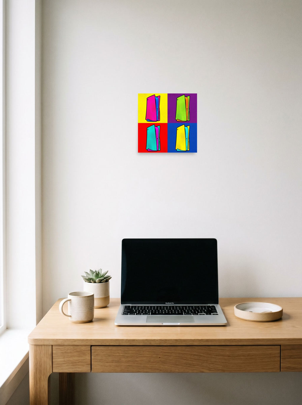 A 10x10 inch unframed paper Pop art print of 'Next Gen Chroma' hanging above a worktable with a laptop.