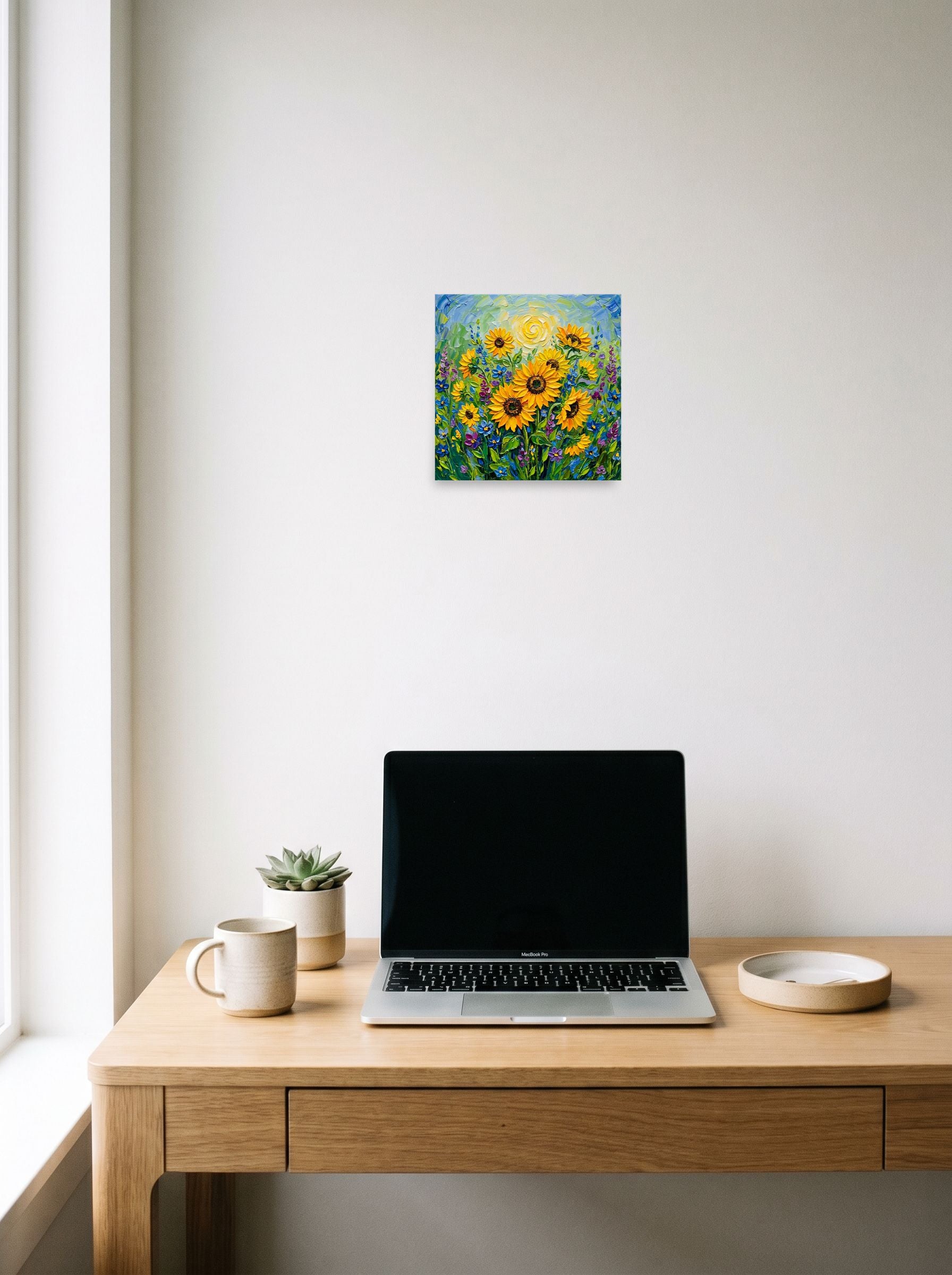 A 10x10 inch unframed paper Impressionism print of 'Sunlit Blooms' hanging above a worktable with a laptop.