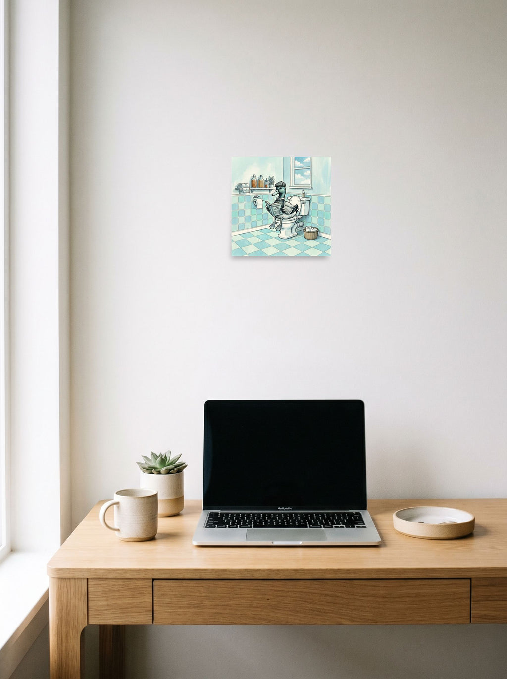 A 10x10 inch unframed paper Lowbrow,Pop art print of 'The Philosophical Duck' hanging above a worktable with a laptop.