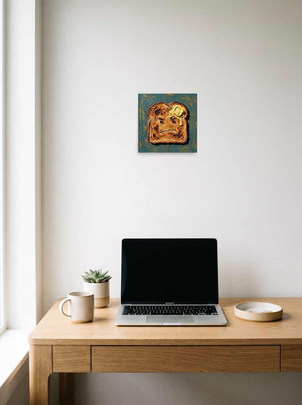 A 10x10 inch unframed paper Pop art,Lowbrow print of 'Morning Grudge' hanging above a worktable with a laptop.
