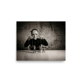 'The Puppeteer of News' — a Surrealism print. Conceptual sepia photograph of a person in a newspaper mask acting as a puppeteer, controlling small human figures on strings against a brick wall, ideal for a moody den or office.