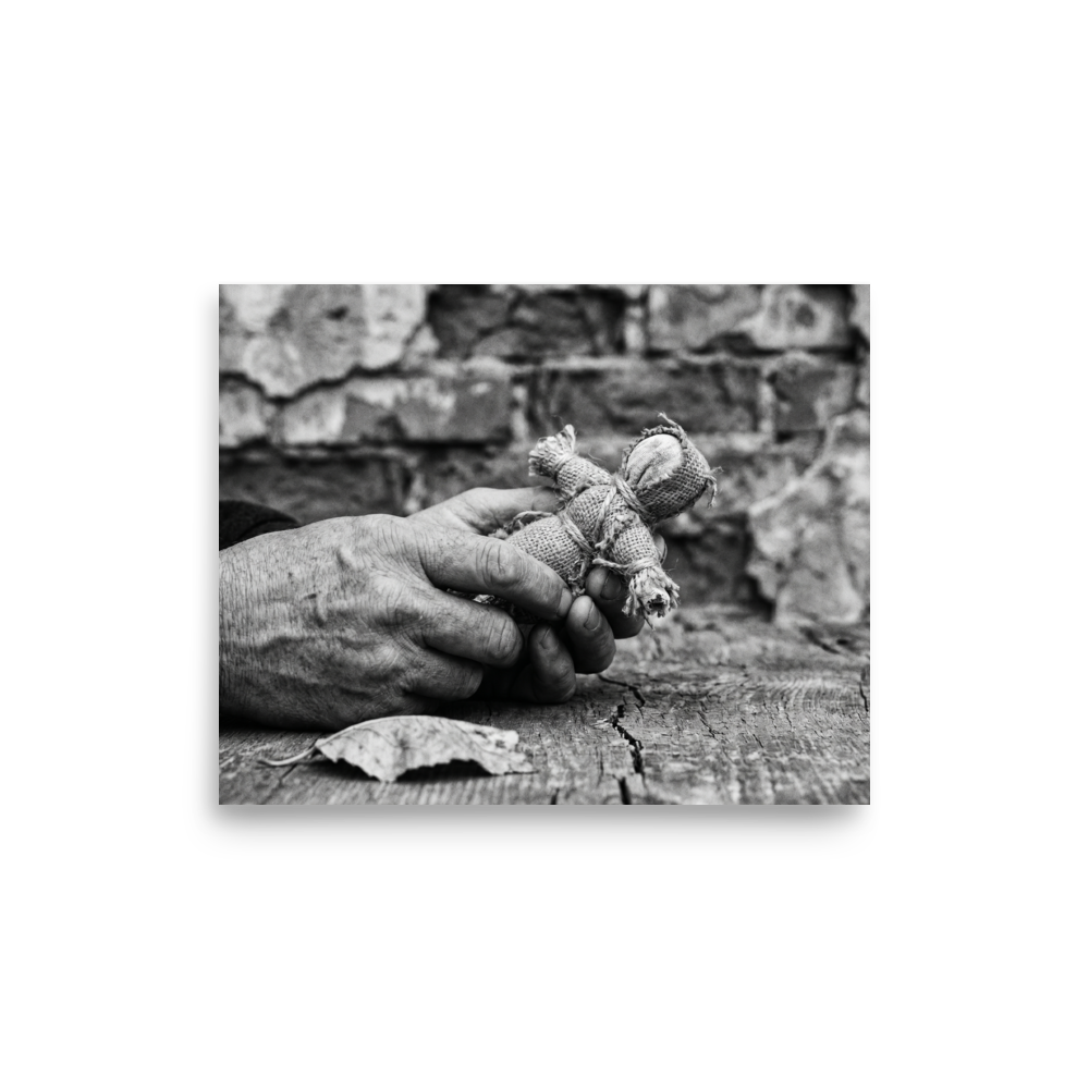 'The Keeper of Memories' — a Art photography print. A black and white photograph of an older person's hands holding a small burlap doll over a cracked wooden table, an atmospheric piece for a Library.