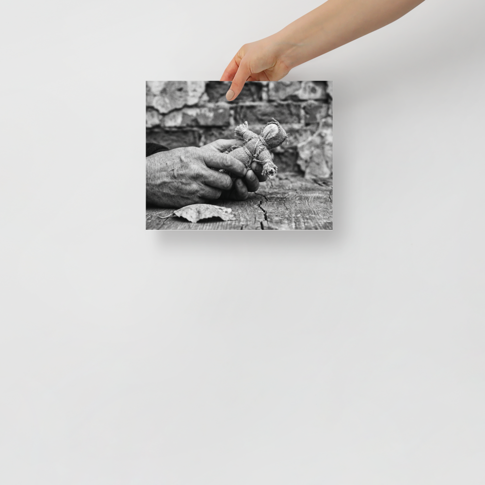 'The Keeper of Memories' — a Art photography print. A black and white photograph of an older person's hands holding a small burlap doll over a cracked wooden table, an atmospheric piece for a Library.