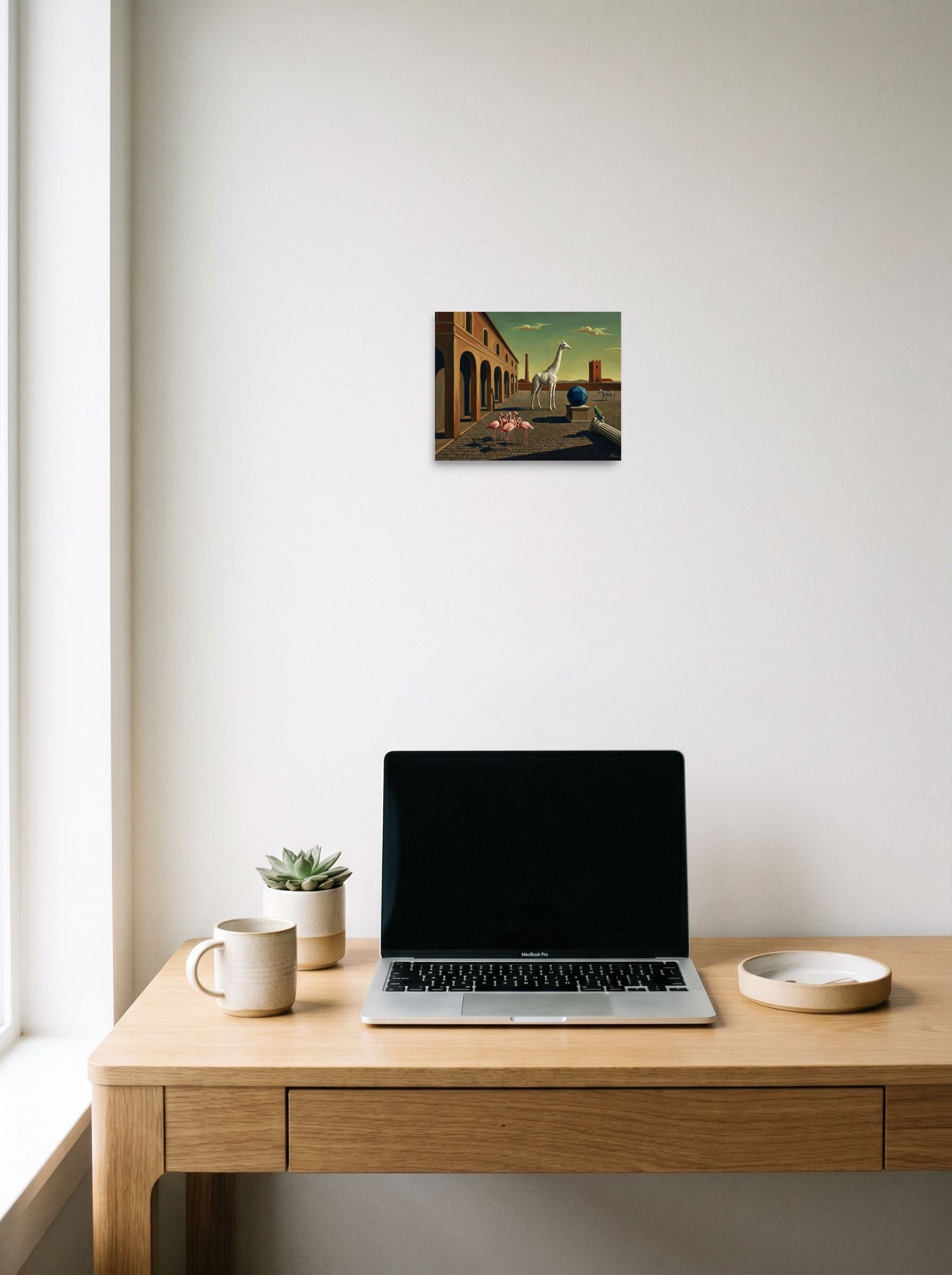 A 10x8 inch unframed paper Surrealism print of 'The Giraffe's Geometry' hanging above a worktable with a laptop.