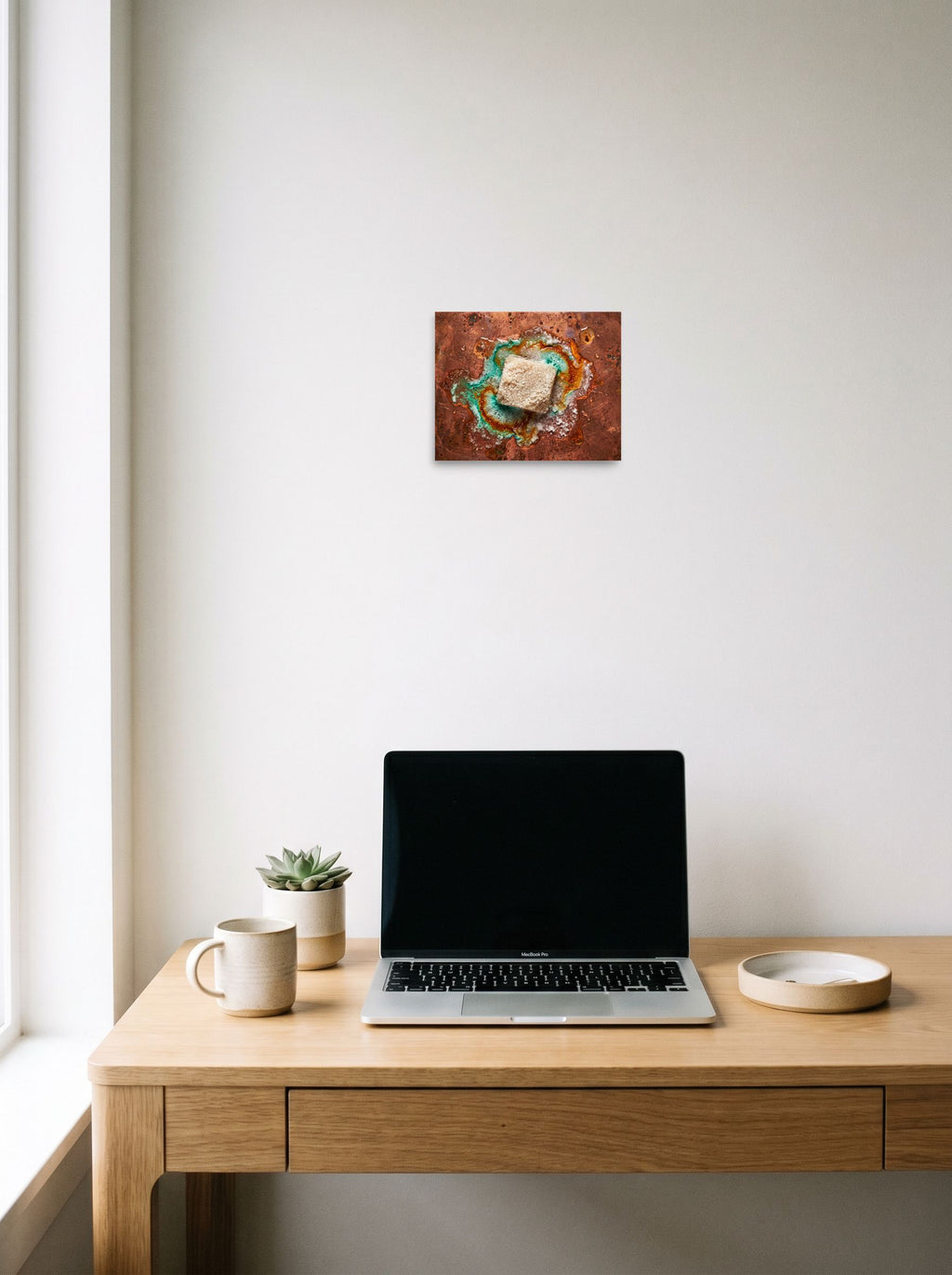 A 10x8 inch unframed paper Art photography print of 'Alchemy of Verdigris' hanging above a worktable with a laptop.