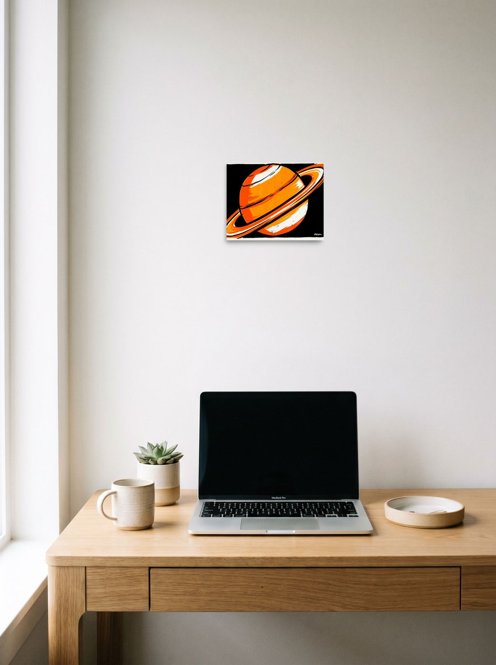 A 10x8 inch unframed paper Pop art print of 'Orange Orbit' hanging above a worktable with a laptop.