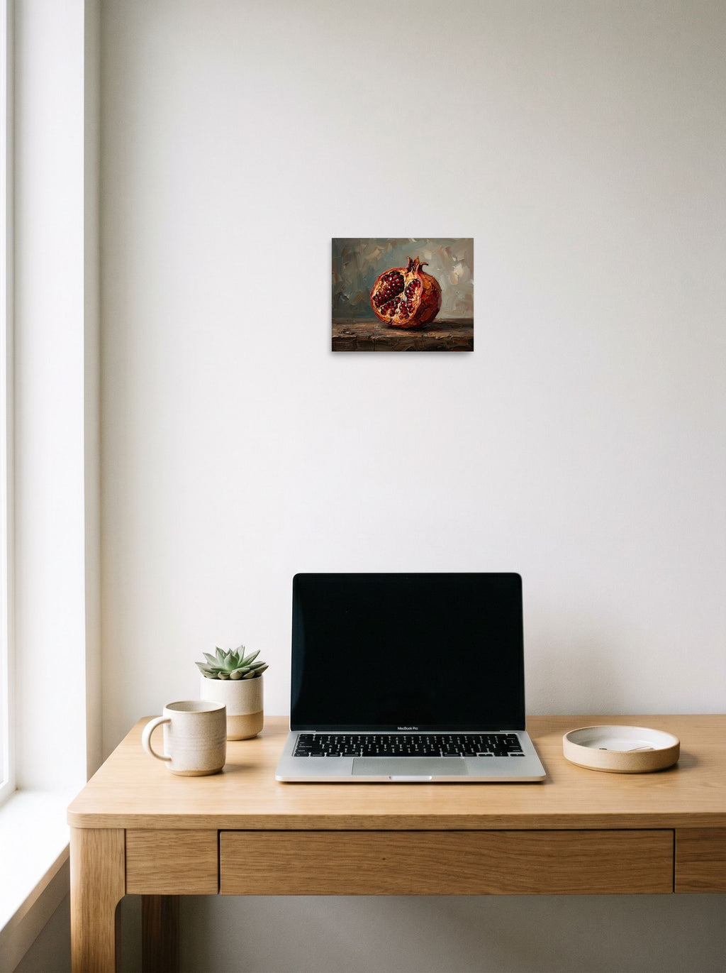 A 10x8 inch unframed paper Realism print of 'The Open Pomegranate' hanging above a worktable with a laptop.