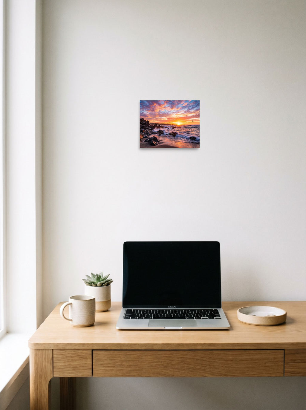 A 10x8 inch unframed paper Art photography print of 'Coastal Fire' hanging above a worktable with a laptop.