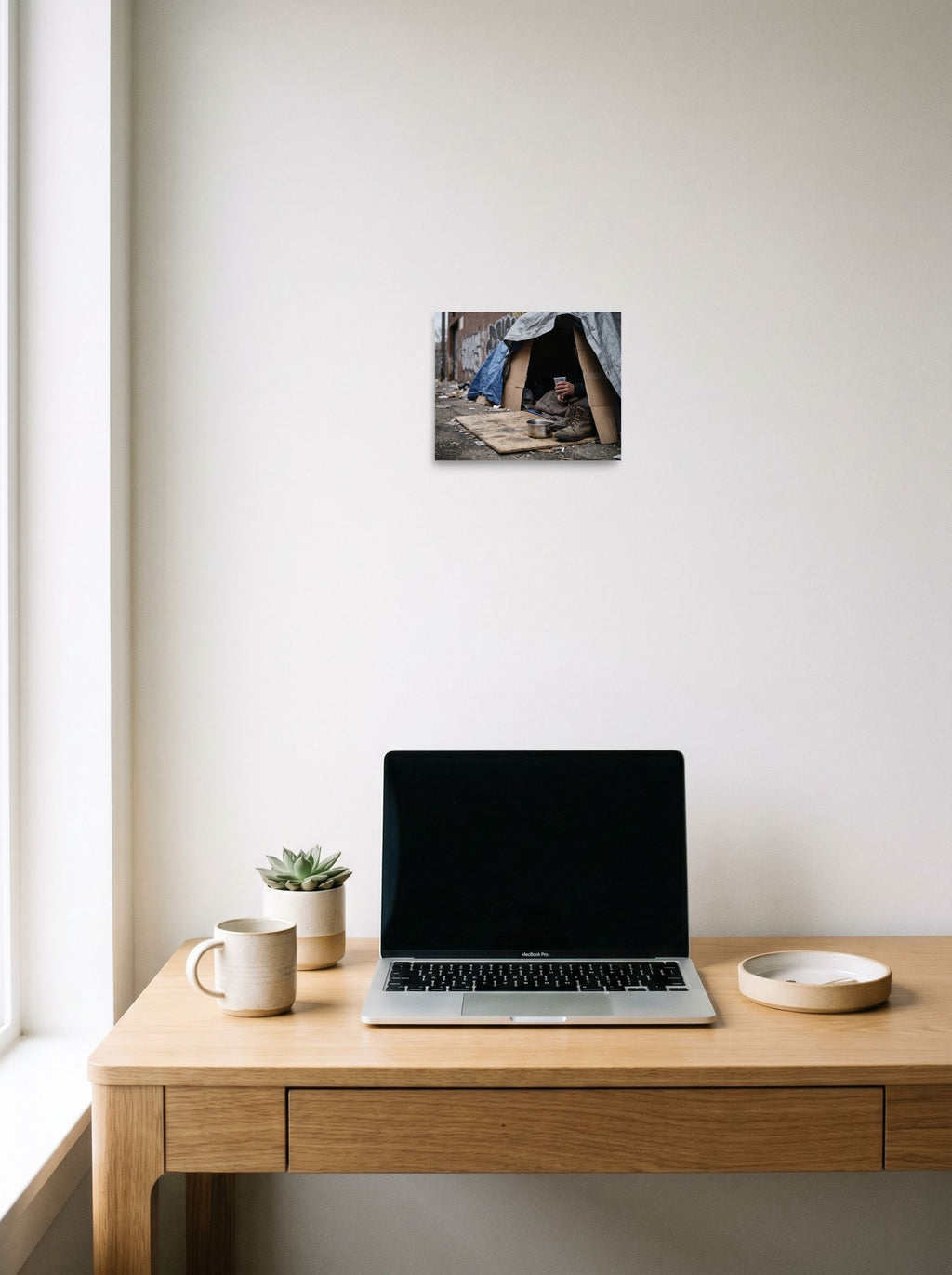 A 10x8 inch unframed paper Art photography print of 'Urban Realities' hanging above a worktable with a laptop.