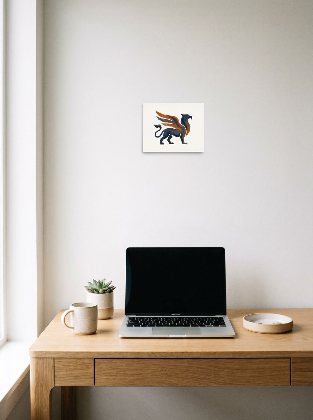 'Guardian Griffin', a Modernism print hanging above a worktable with a laptop. Shown as unframed paper, 10x8 inch.