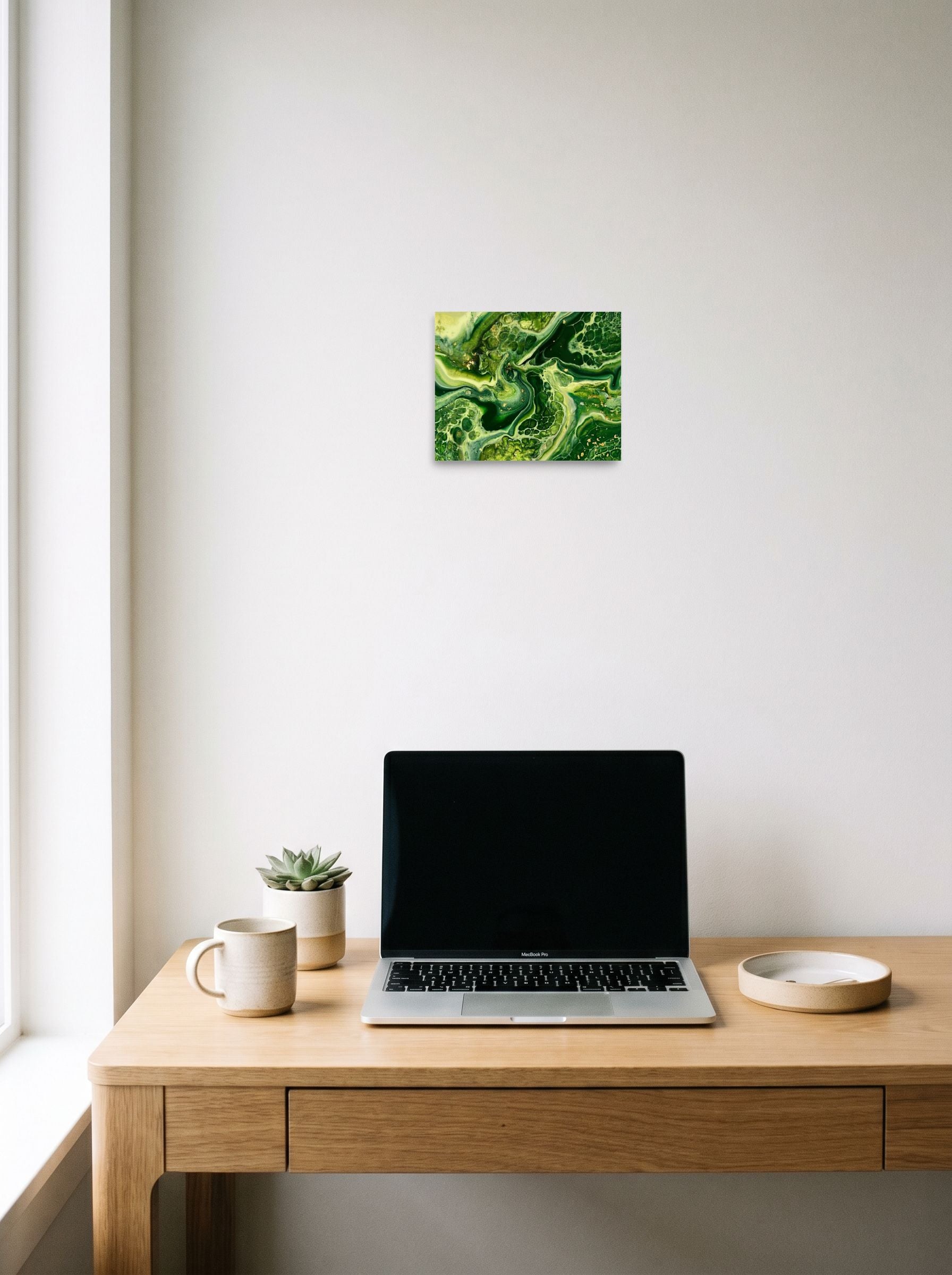 A 10x8 inch unframed paper Abstract art print of 'Emerald Flow' hanging above a worktable with a laptop.