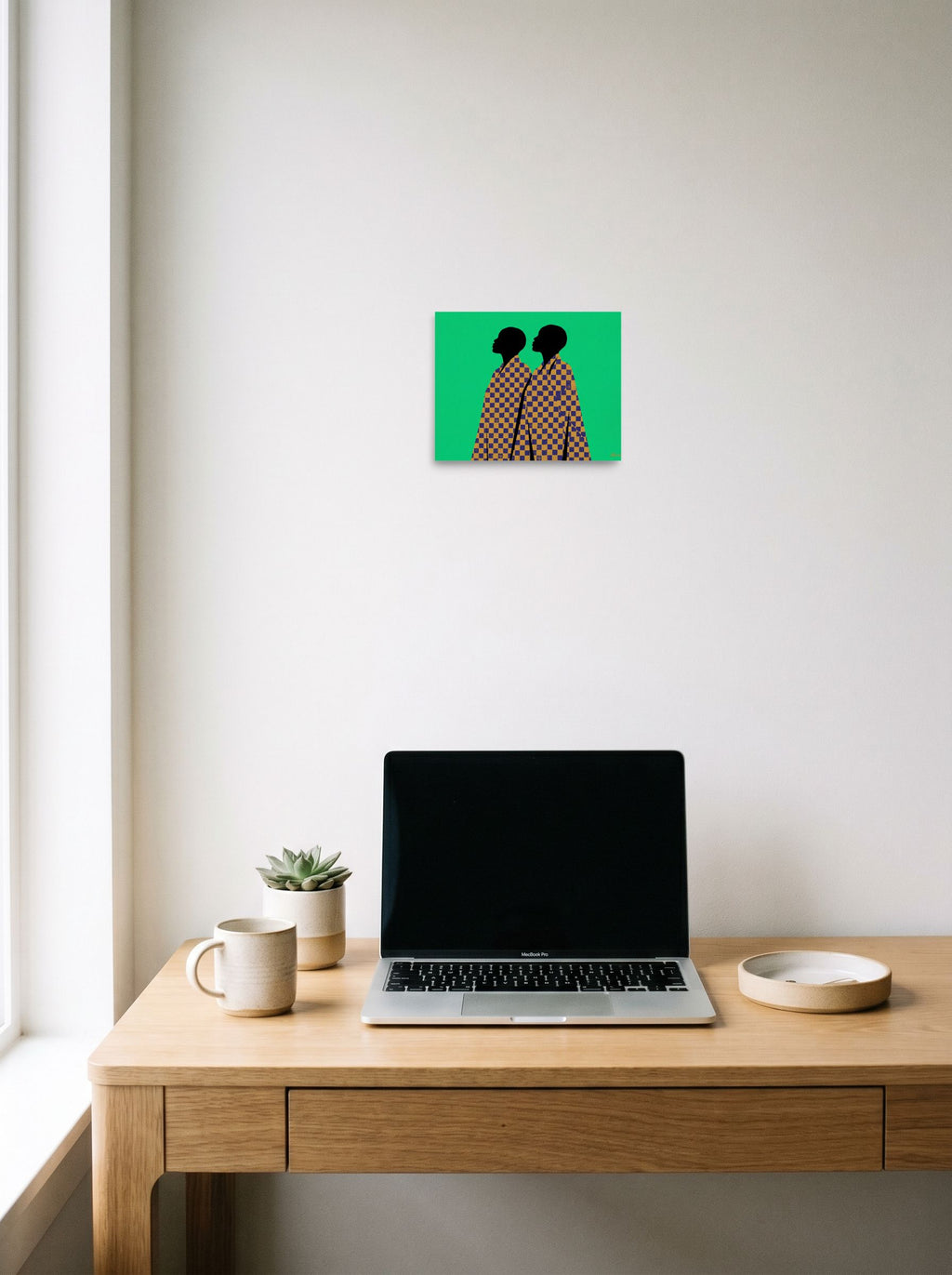 A 10x8 inch unframed paper Afrofuturism,Pop art print of 'Checkered Solidarity' hanging above a worktable with a laptop.