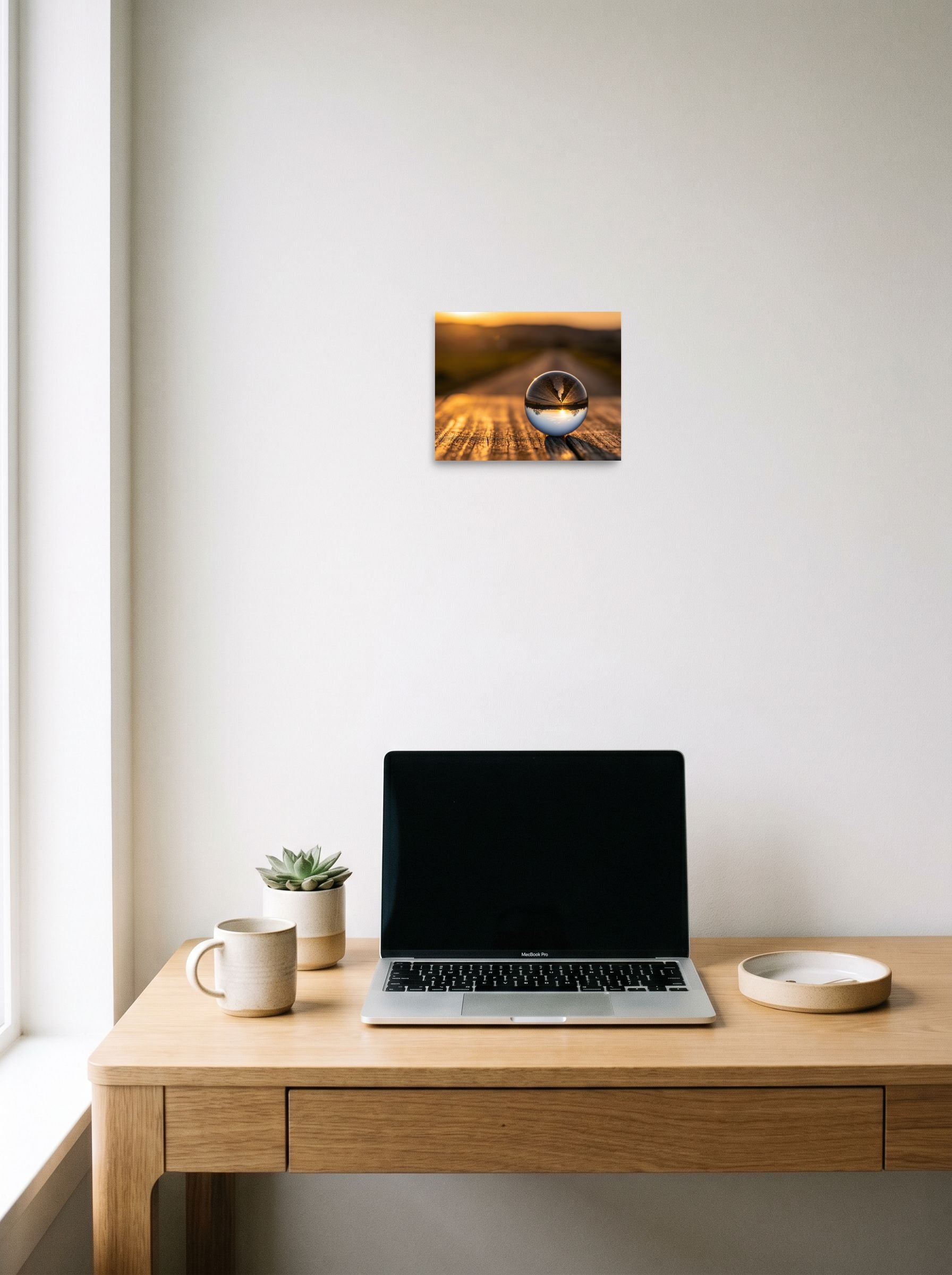 A 10x8 inch unframed paper Surrealism print of 'Inverted Sunset' hanging above a worktable with a laptop.