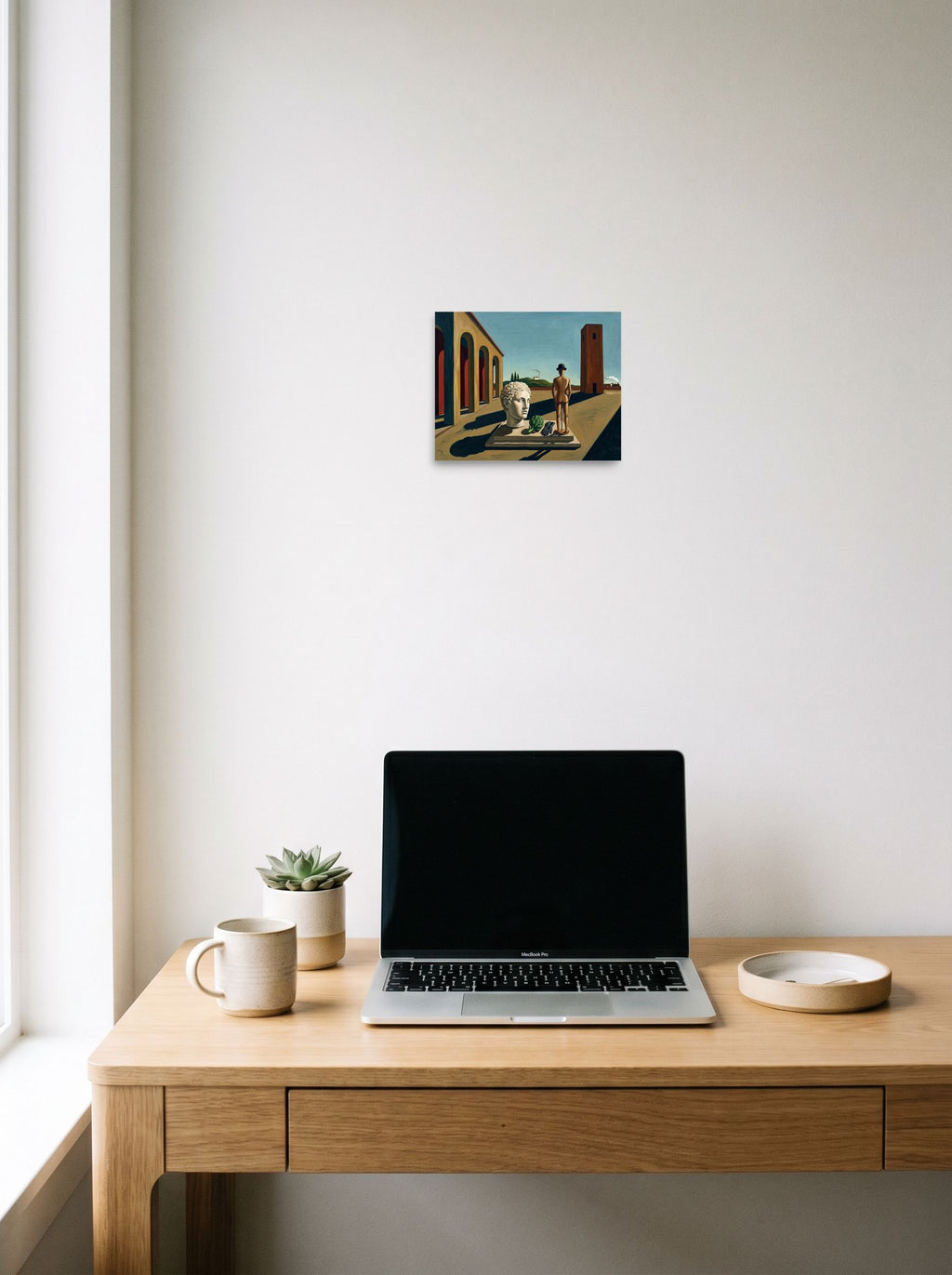 A 10x8 inch unframed paper Metaphysical painting print of 'The Enigma of the Industrial Mind' hanging above a worktable with a laptop.