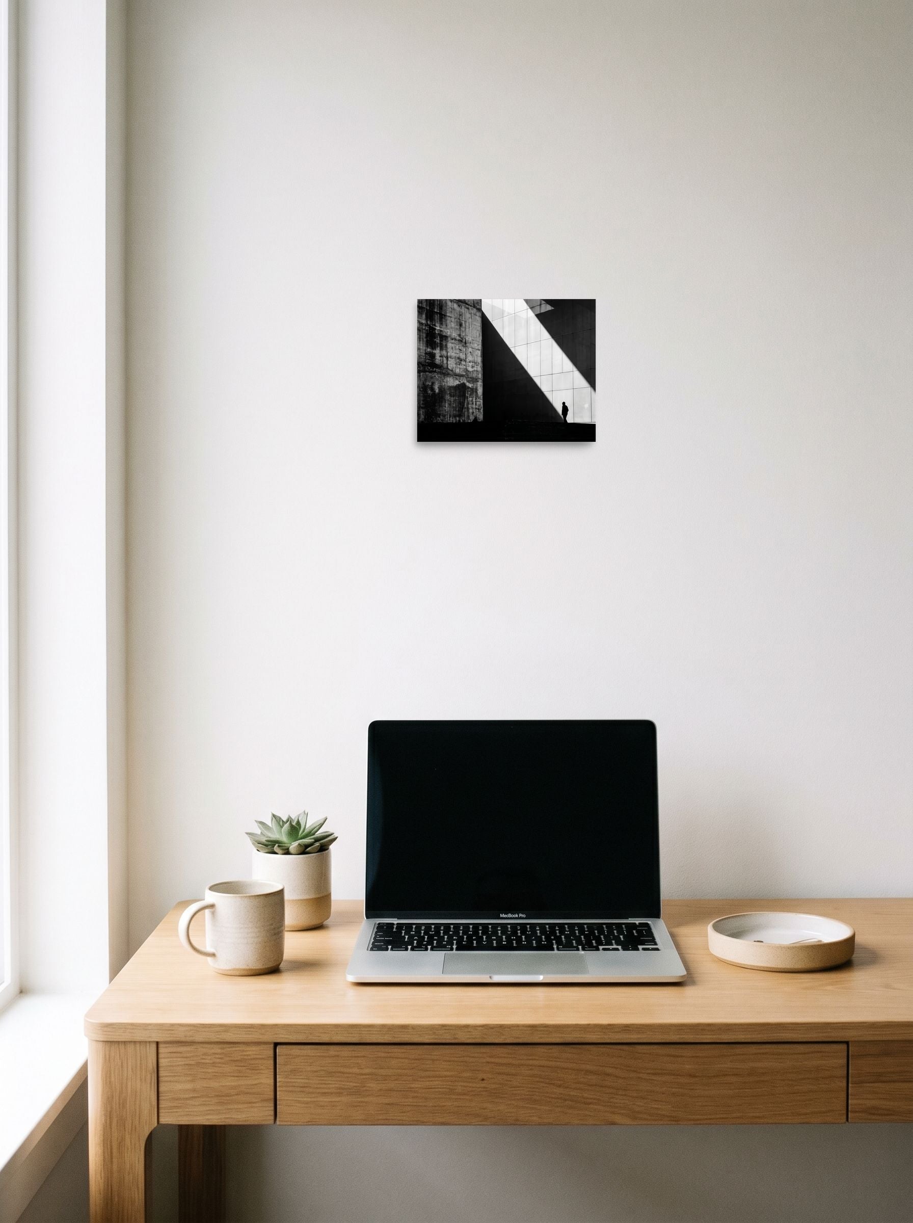 A 10x8 inch unframed paper Modernism print of 'Urban Geometry' hanging above a worktable with a laptop.