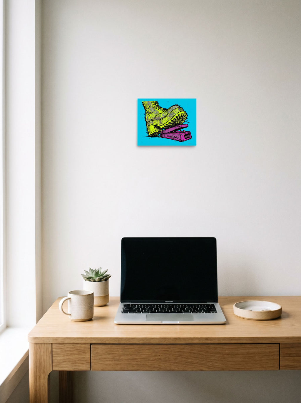 A 10x8 inch unframed paper Pop art print of 'Stomp the Fuzz' hanging above a worktable with a laptop.