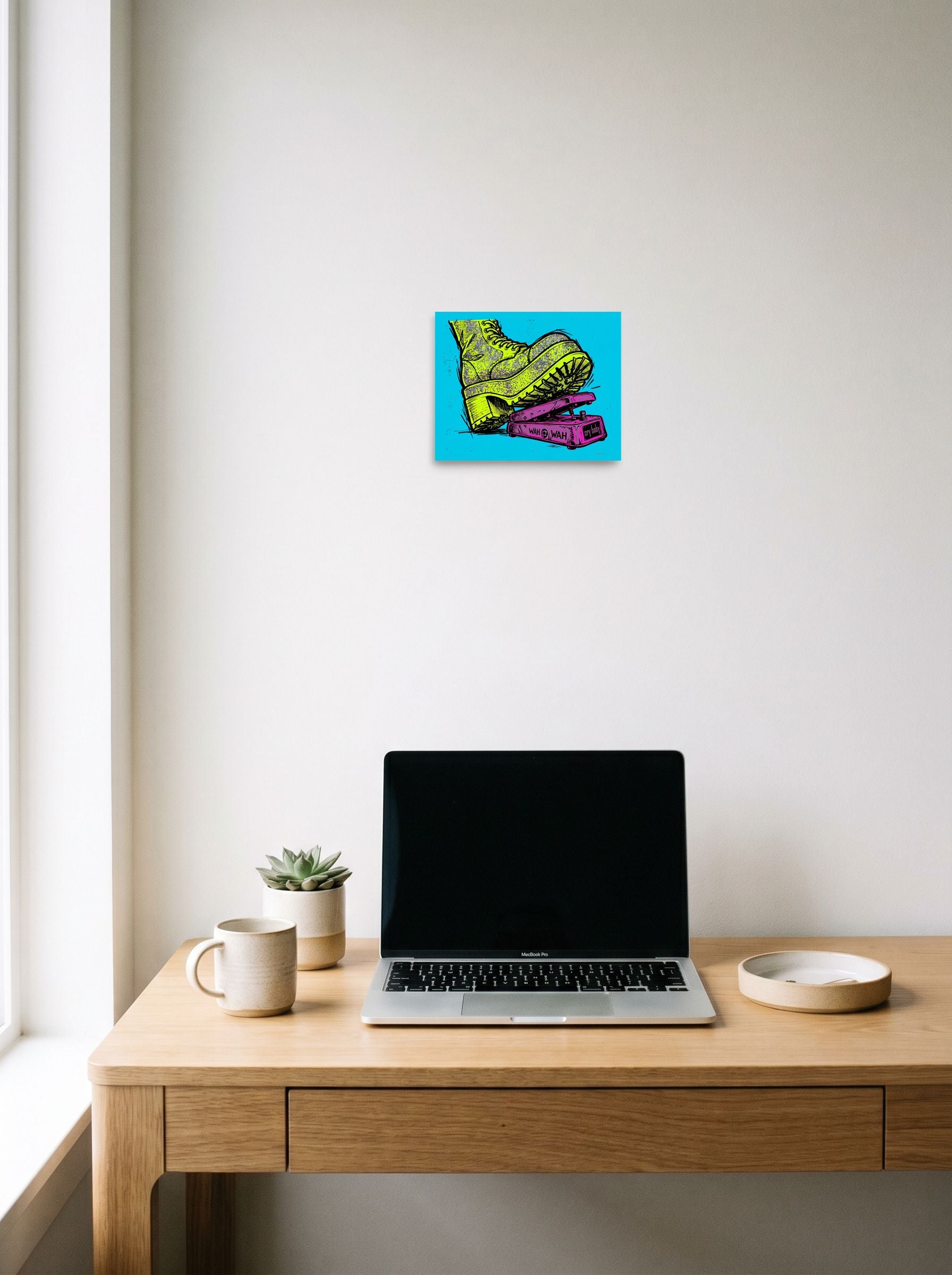 A 10x8 inch unframed paper Pop art print of 'Stomp the Fuzz' hanging above a worktable with a laptop.