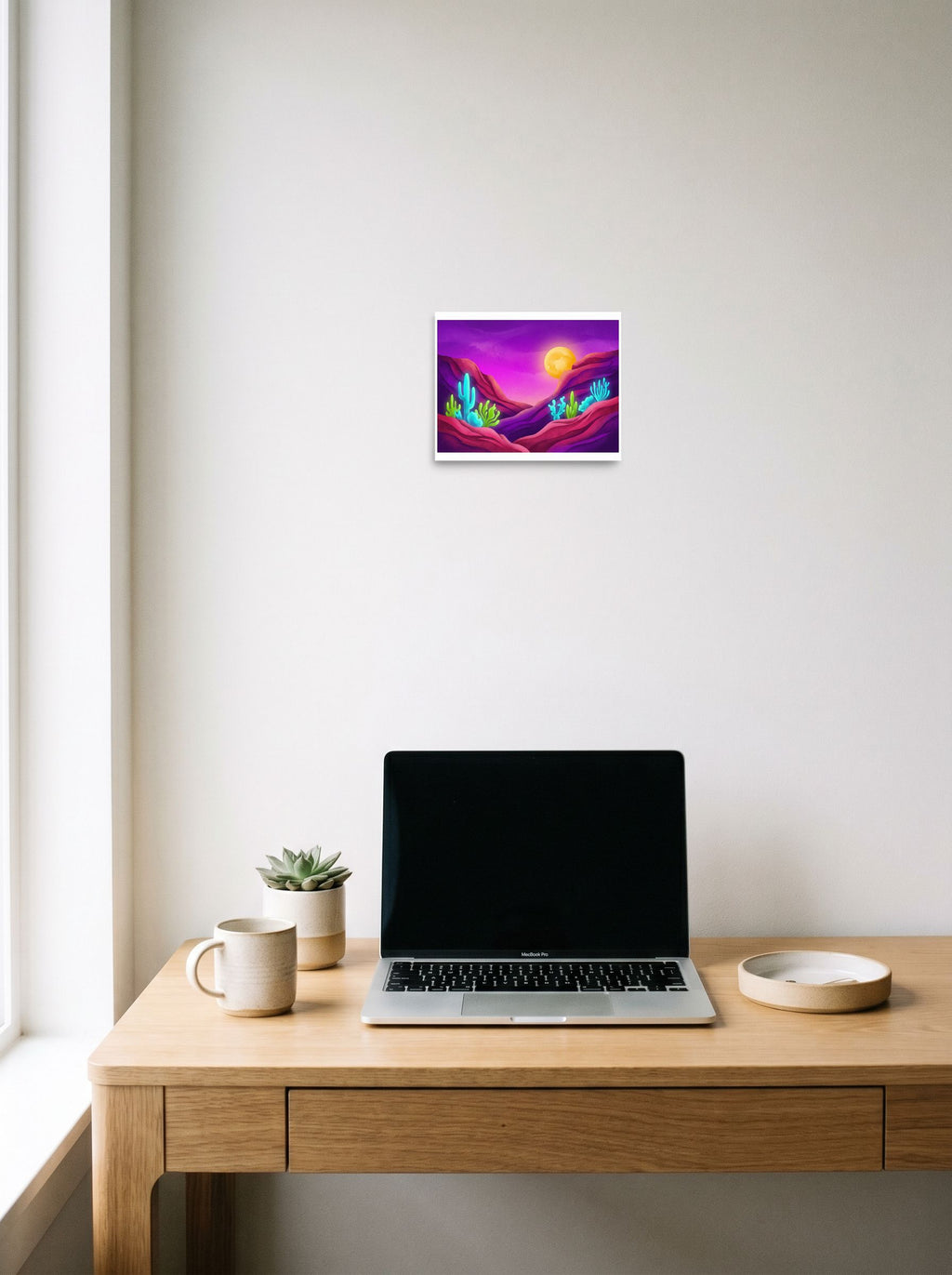 A 10x8 inch unframed paper Surrealism,Psychedelic art print of 'Bioluminescent Desert' hanging above a worktable with a laptop.