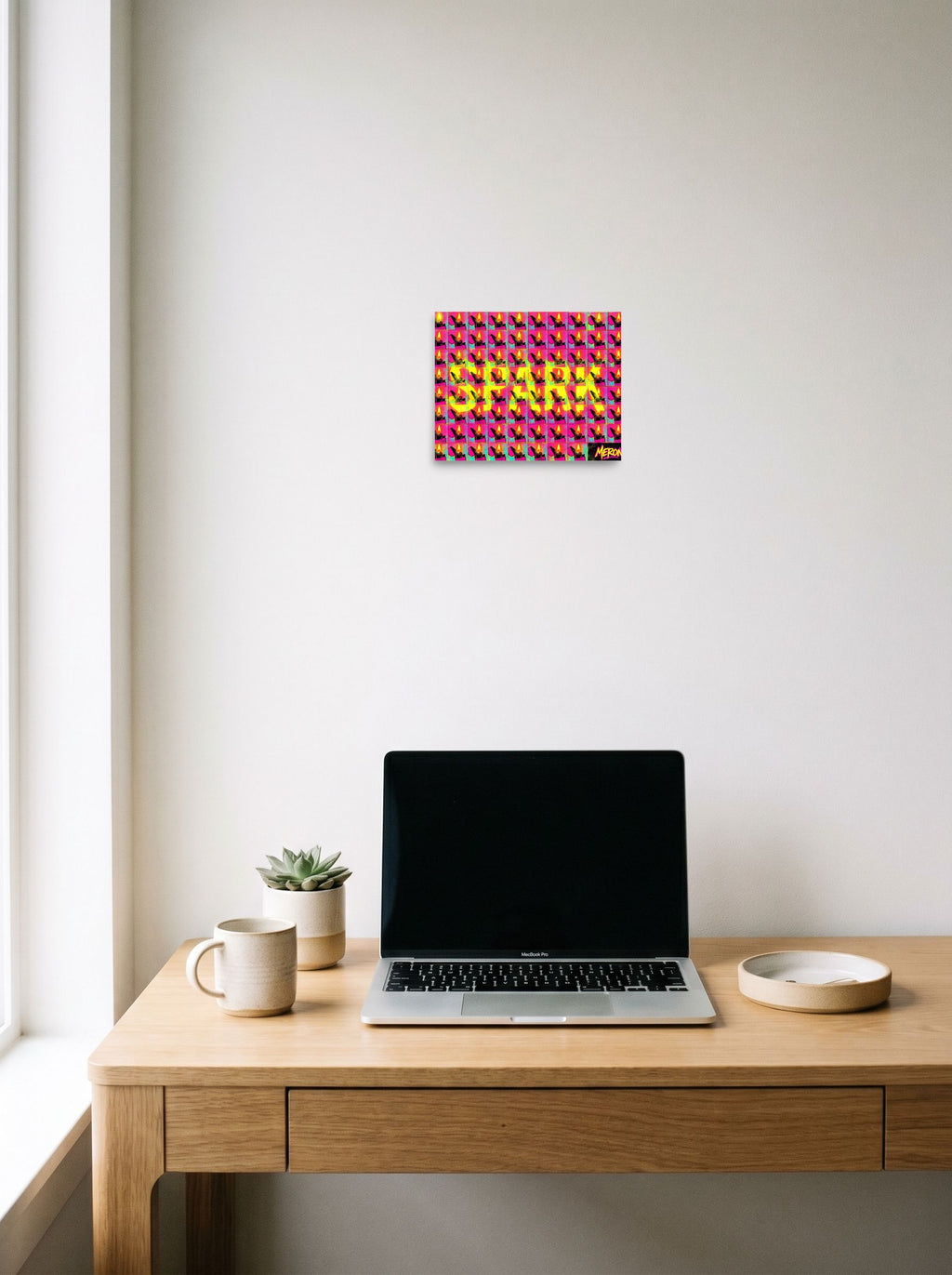 A 10x8 inch unframed paper Pop art print of 'Magenta Spark Grid' hanging above a worktable with a laptop.