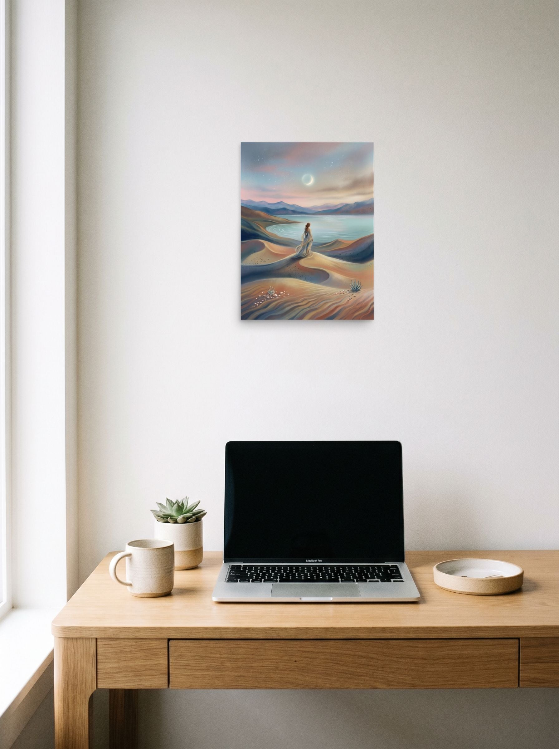A 12x16 inch unframed paper Magic realism print of 'Desert Moonrise' hanging above a worktable with a laptop.