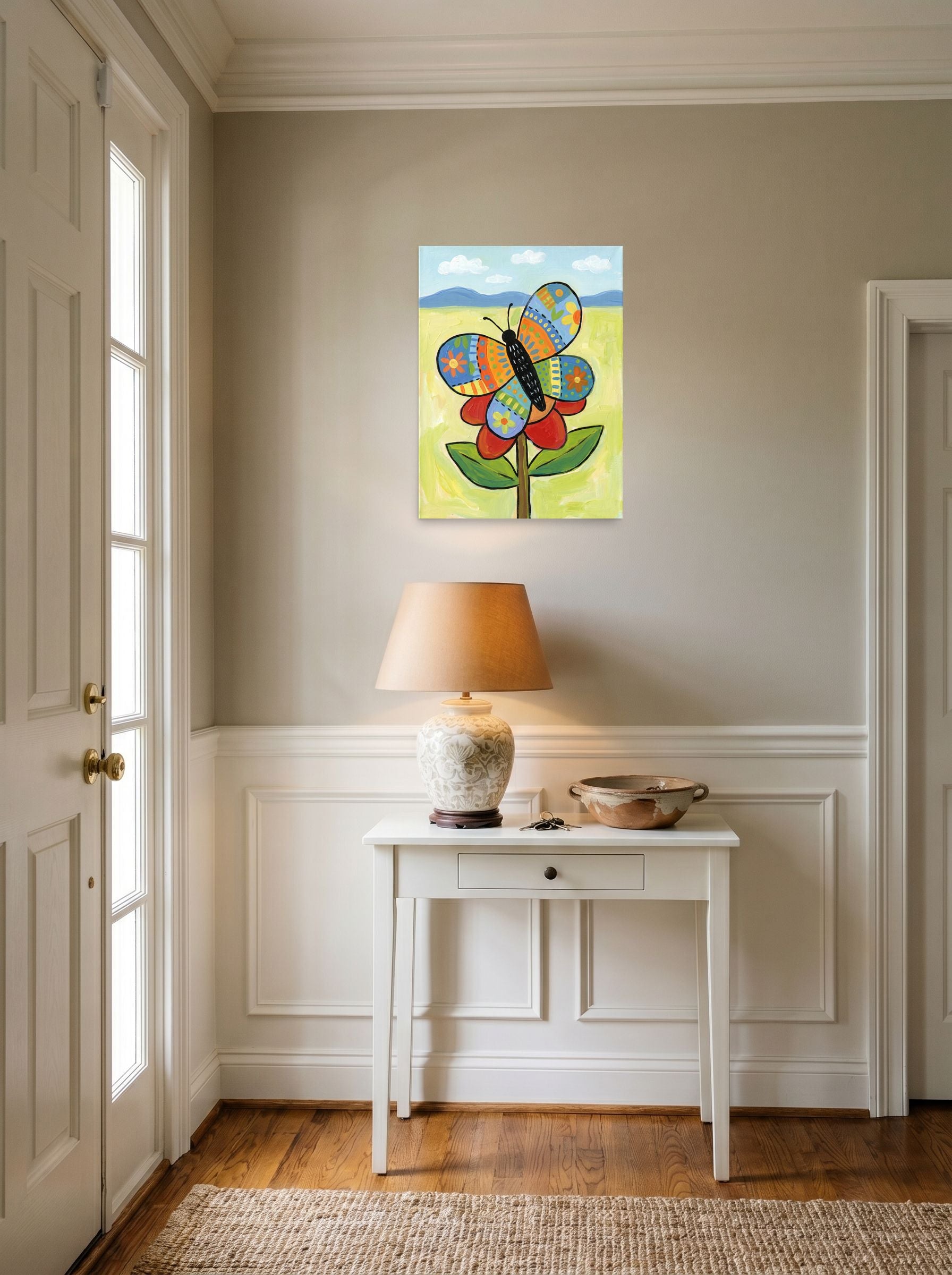 A 18x24 inch unframed paper Naive art print of 'The Patchwork Butterfly' hanging in an entryway near a console.
