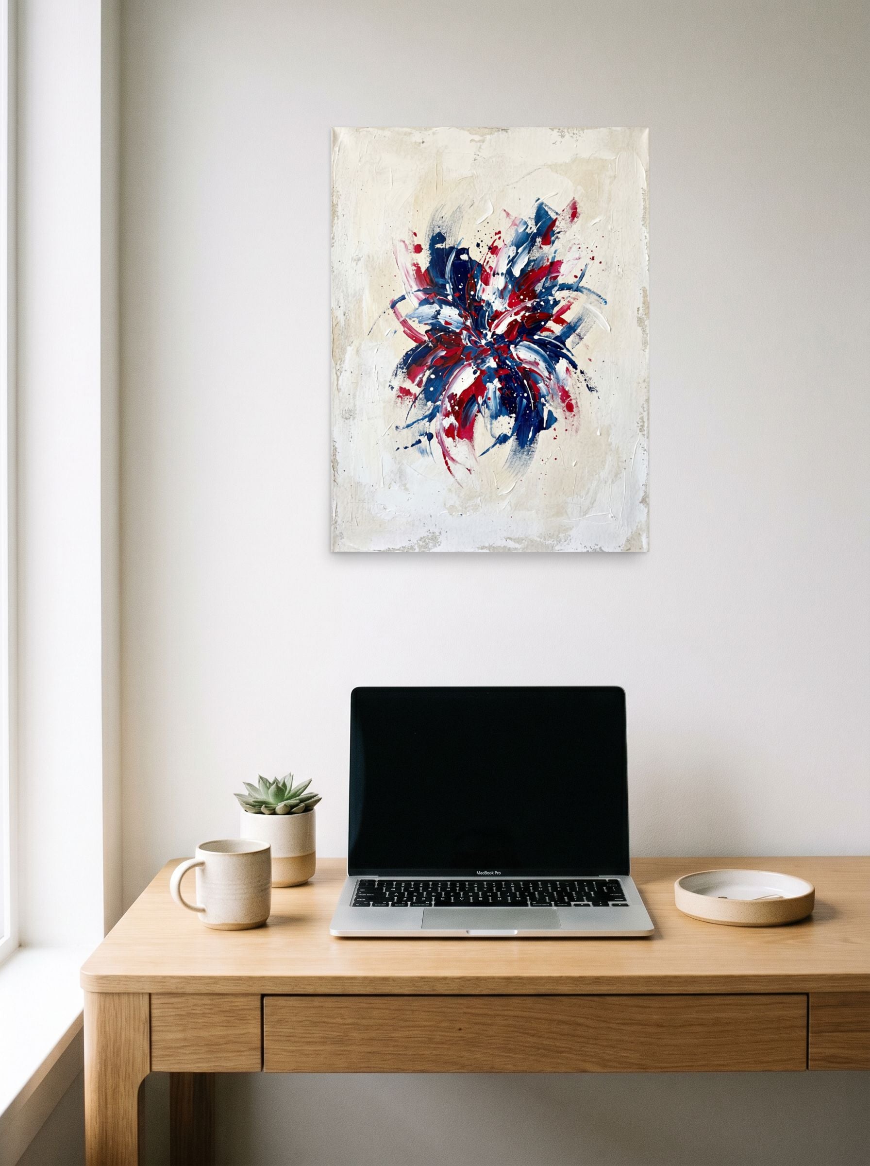 A 18x24 inch unframed paper Abstract expressionism print of 'Patriotic Burst' hanging above a worktable with a laptop.