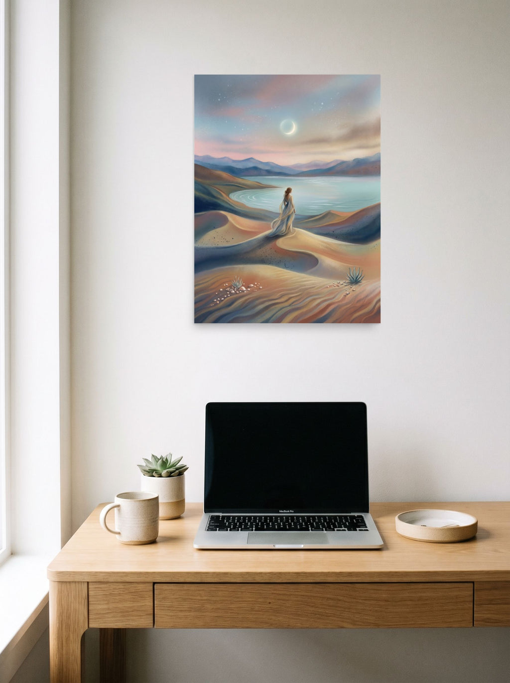 A 18x24 inch unframed paper Magic realism print of 'Desert Moonrise' hanging above a worktable with a laptop.