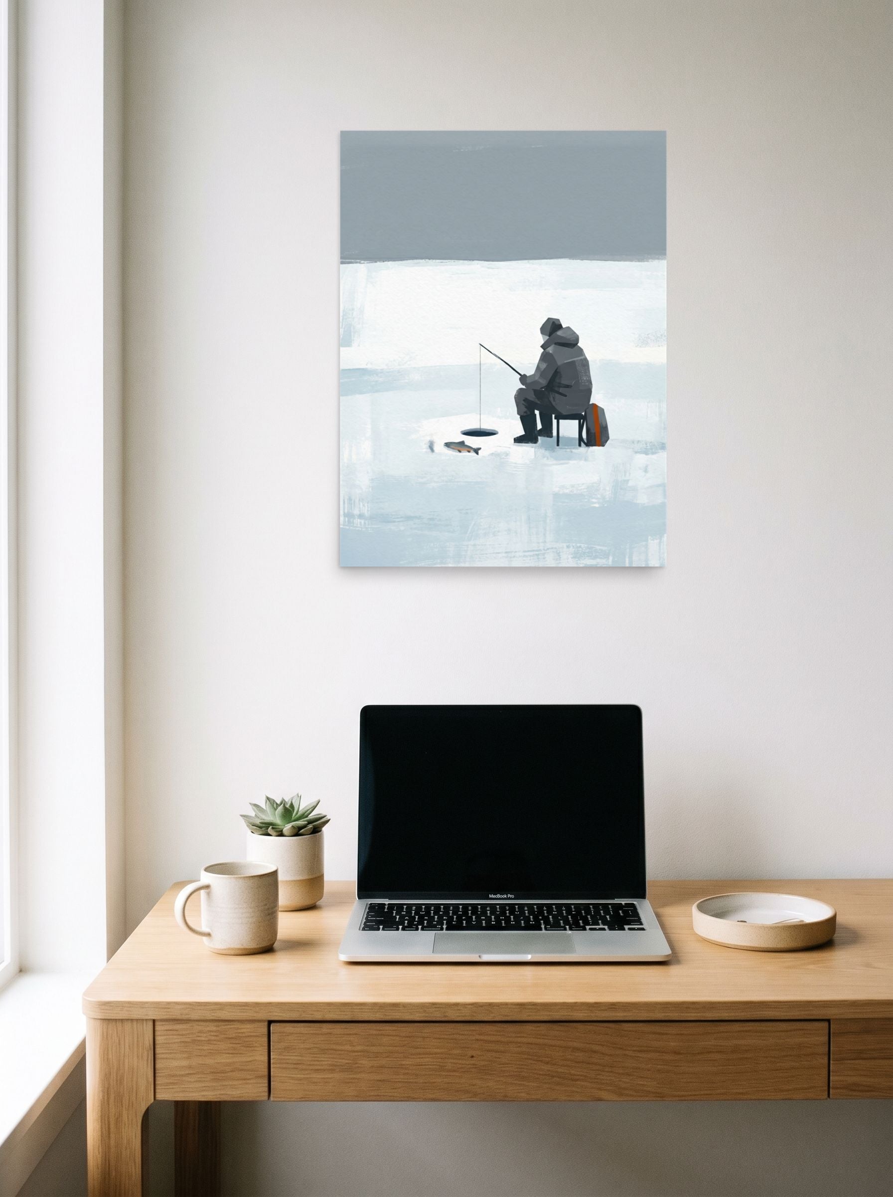 A 18x24 inch unframed paper Minimalism print of 'Winter Solitude' hanging above a worktable with a laptop.