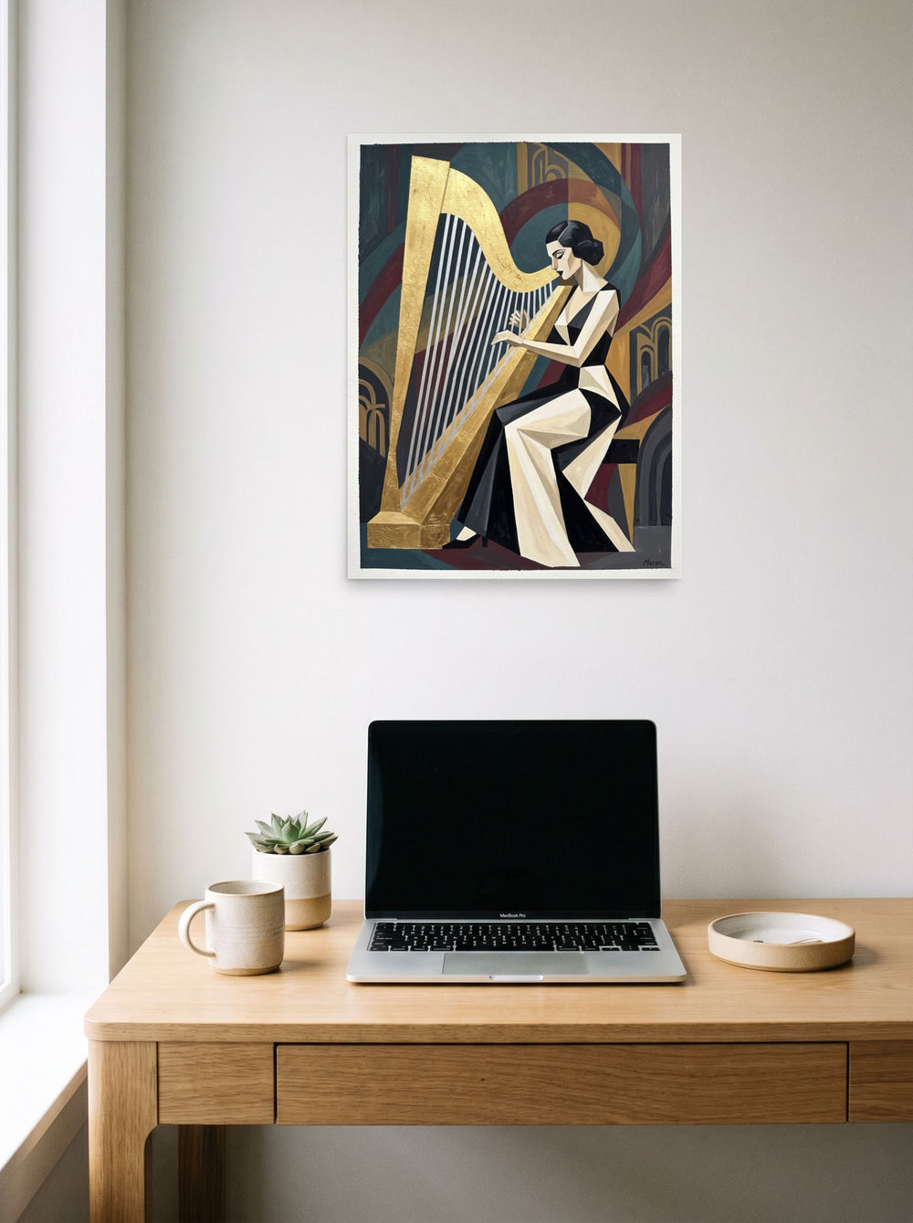 A 18x24 inch unframed paper Art Deco print of 'The Golden Harpist' hanging above a worktable with a laptop.
