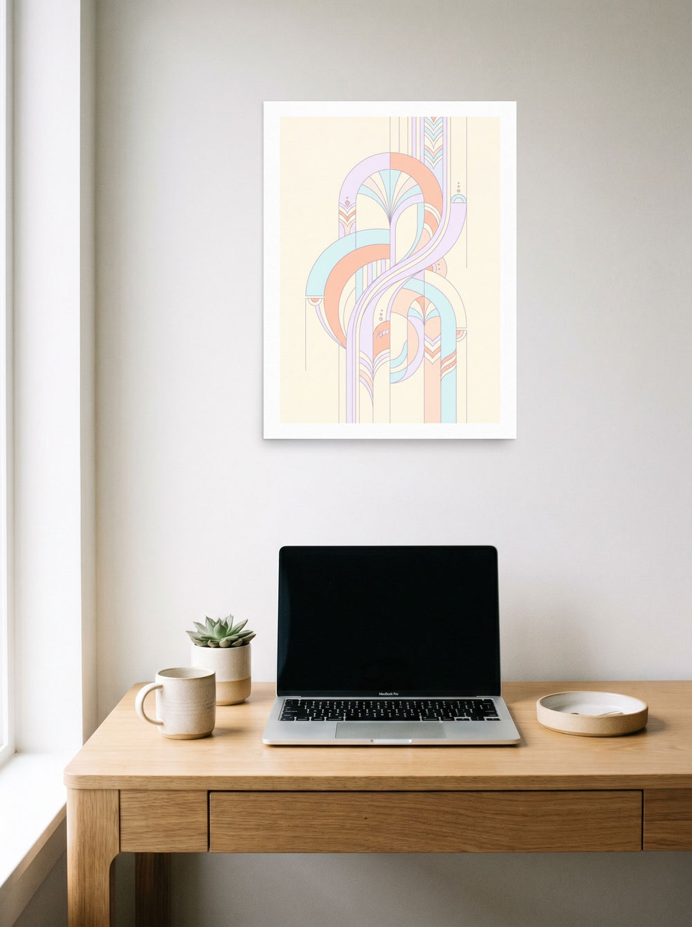 A 18x24 inch unframed paper Art Deco print of 'Pastel Deco Flow' hanging above a worktable with a laptop.