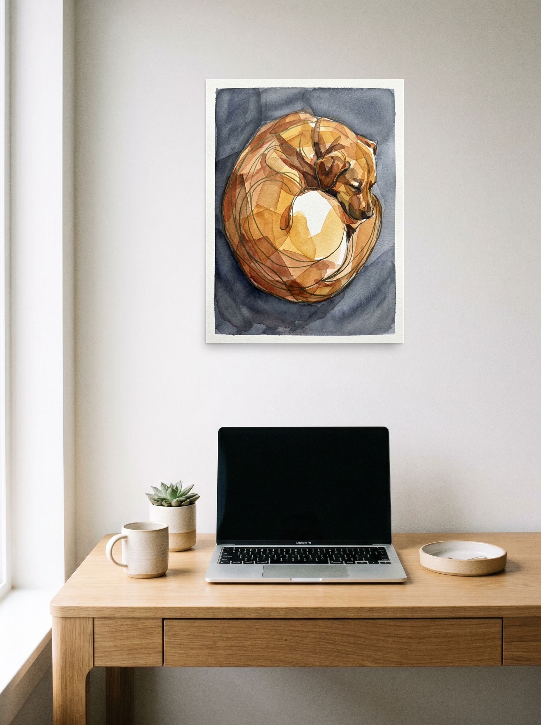 A 18x24 inch unframed paper Cubism print of 'The Sleeping Dog' hanging above a worktable with a laptop.