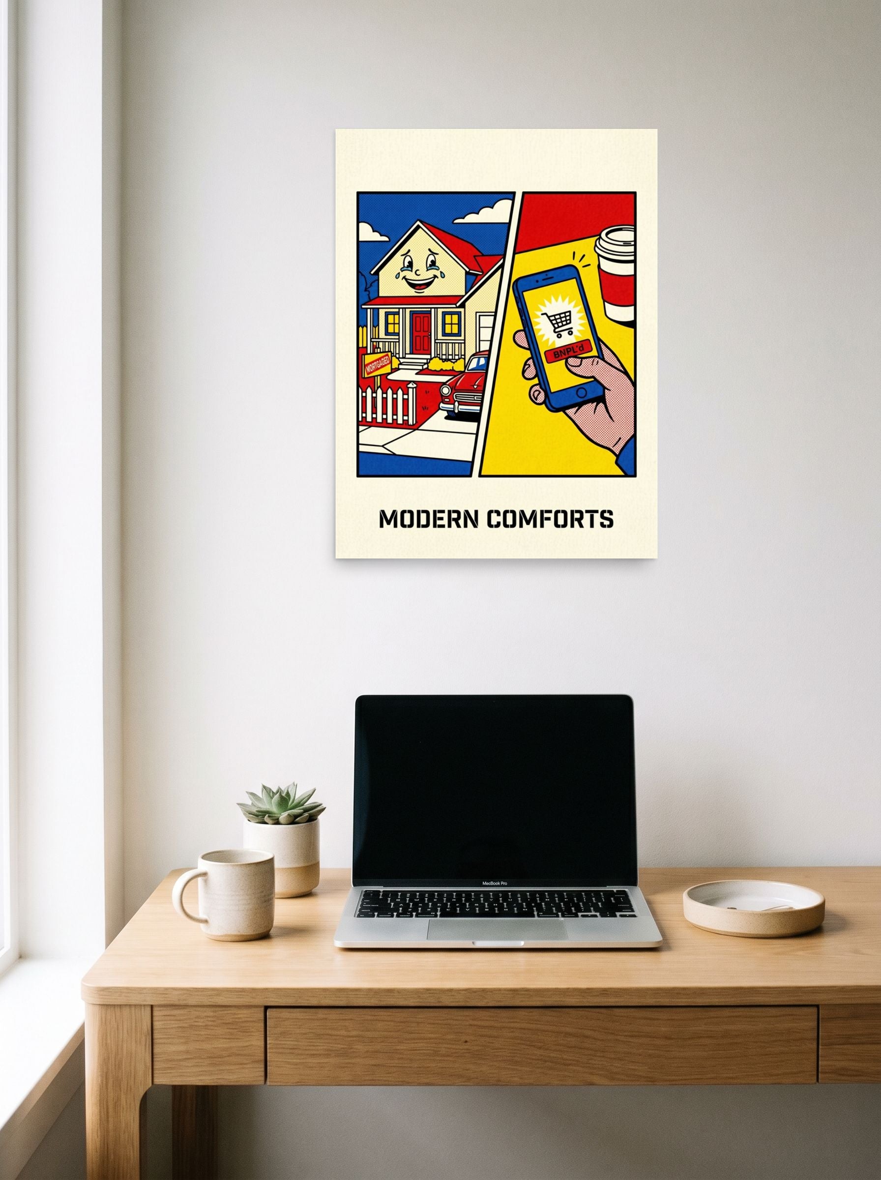A 18x24 inch unframed paper Pop art print of 'Modern Comforts' hanging above a worktable with a laptop.