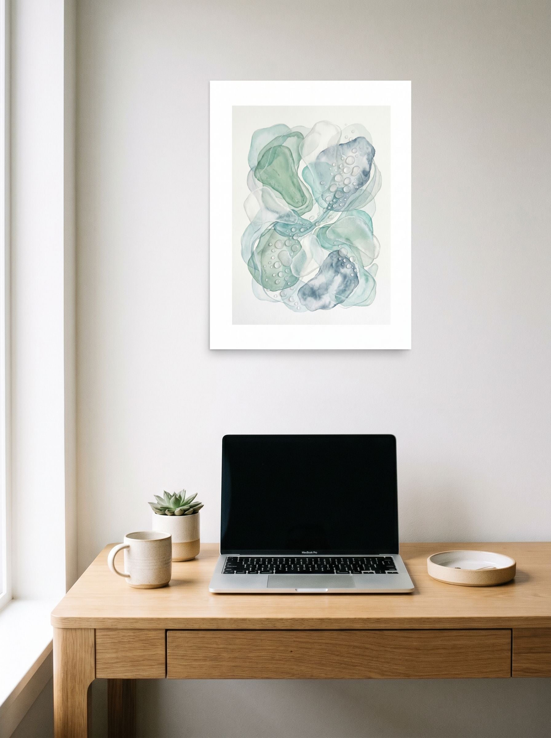 A 18x24 inch unframed paper Minimalism,Abstract art print of 'Morning Dew' hanging above a worktable with a laptop.
